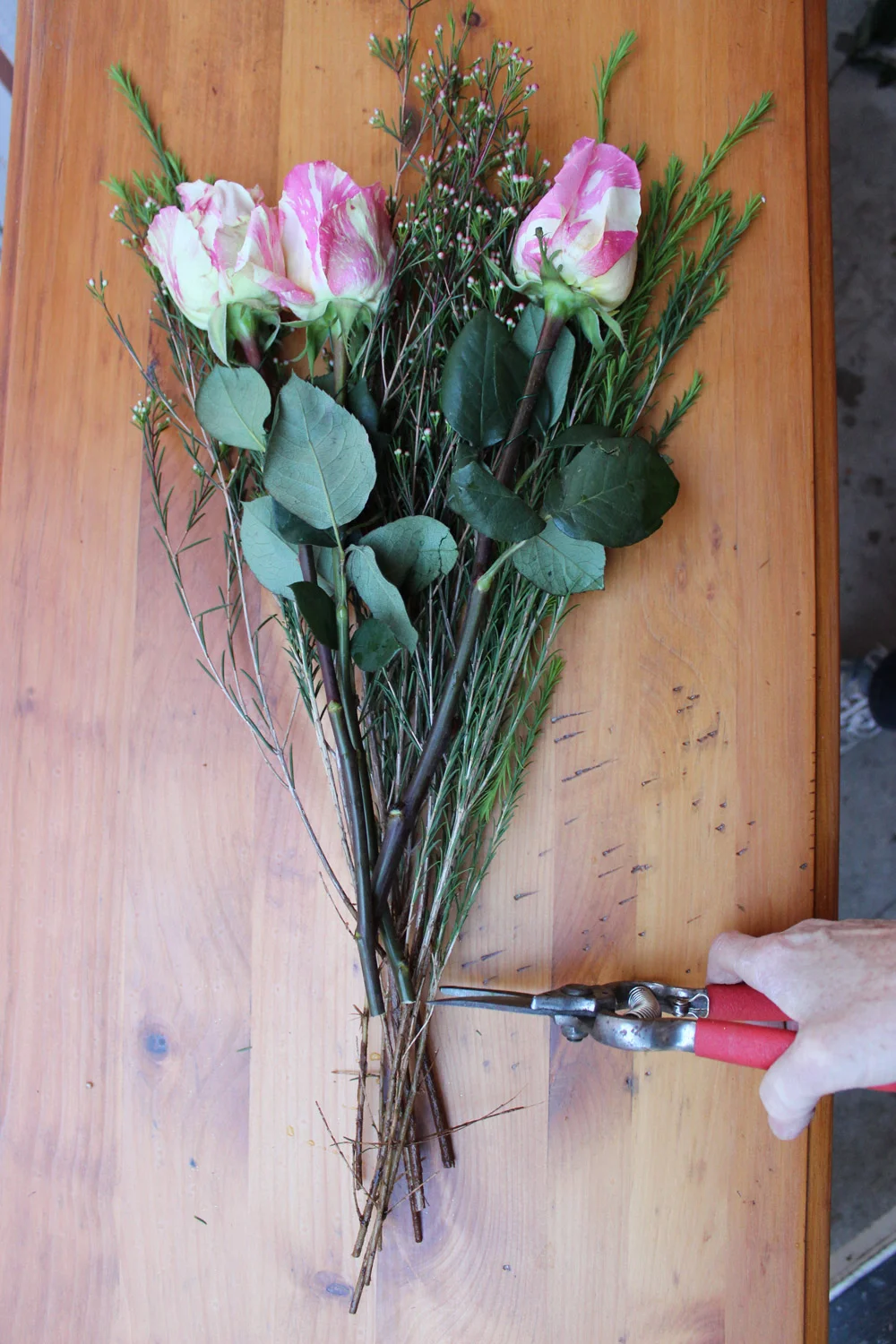 Make a grouping of 3 candy cane roses and some wax flower buds.  Cut the wax flower bud stalks the same height as the roses.  Place this grouping in the front of your vase.