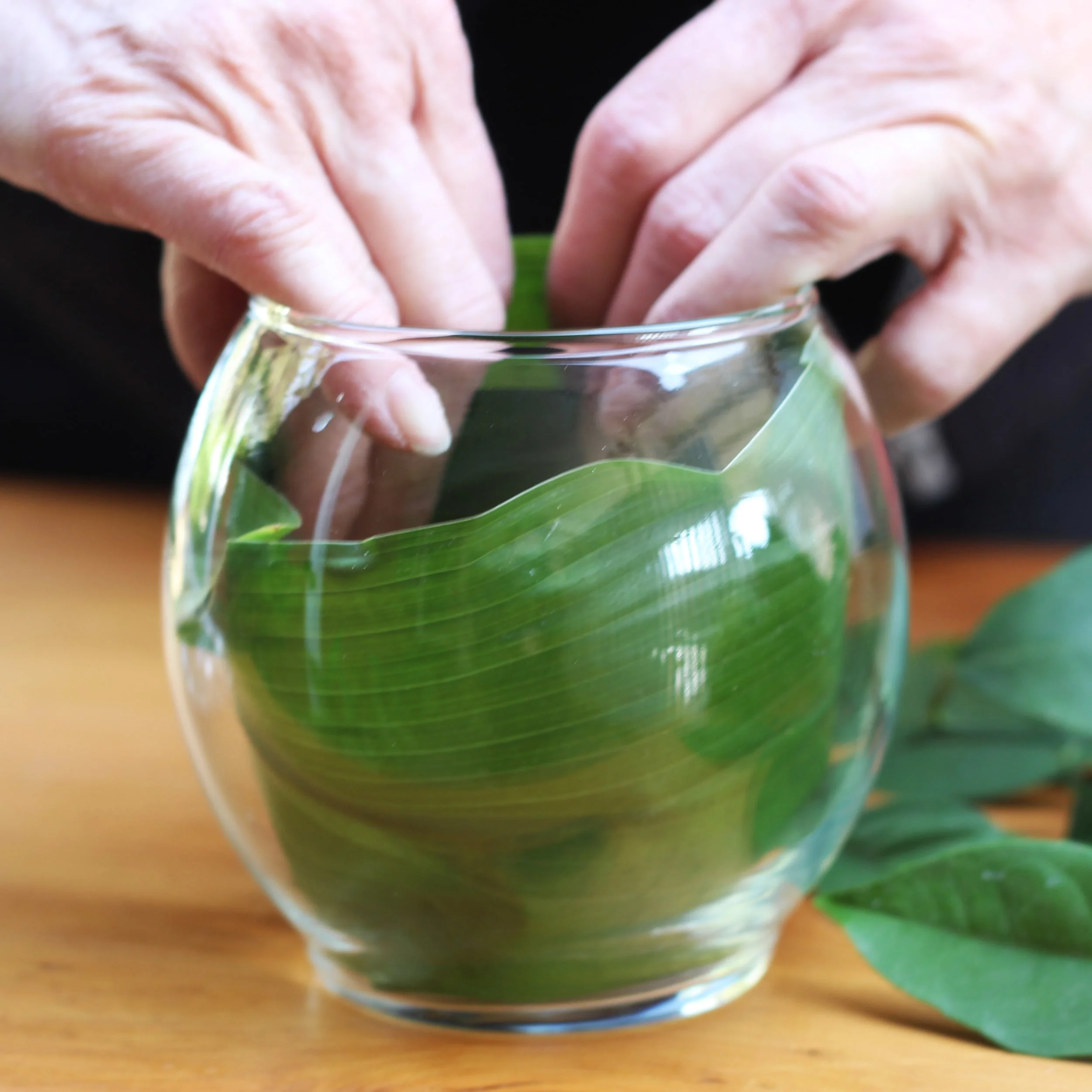 Form a cylindrical shape with leaf and fit into vase, pressing it tight against the glass.