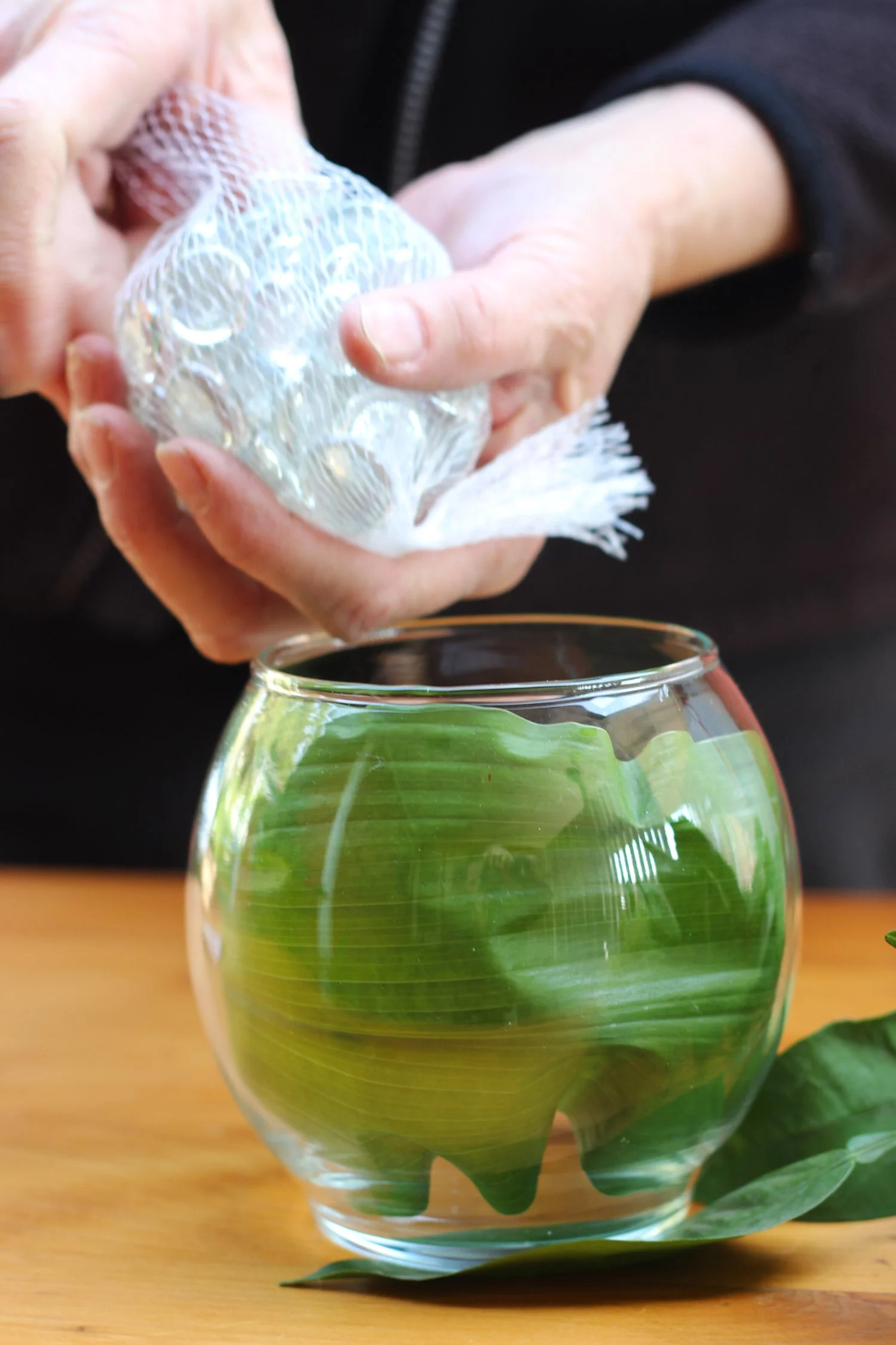 Pour small bag of flat clear marble in bottom on vase.