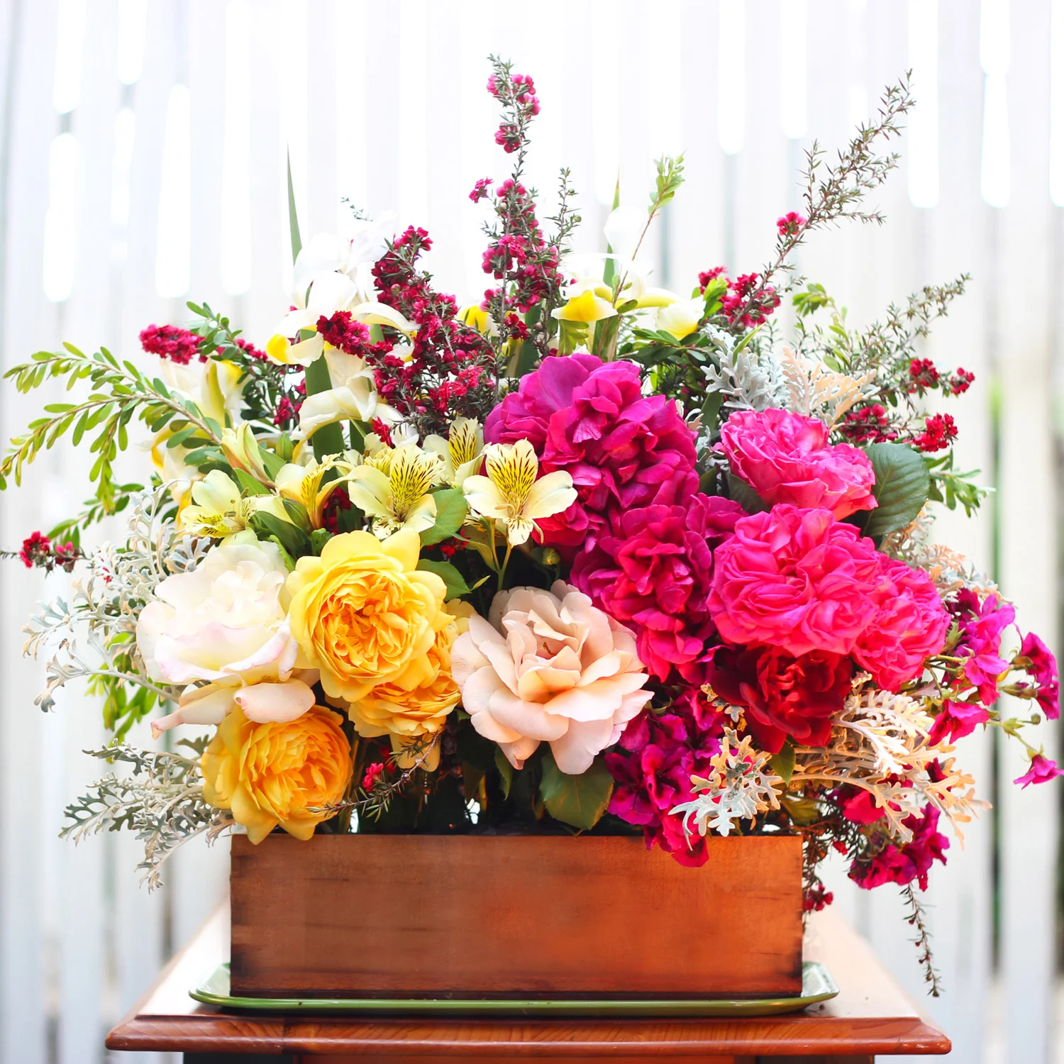 Place 'anchor' flower center front.  Fill in with roses, geraniums, and dusty miller.