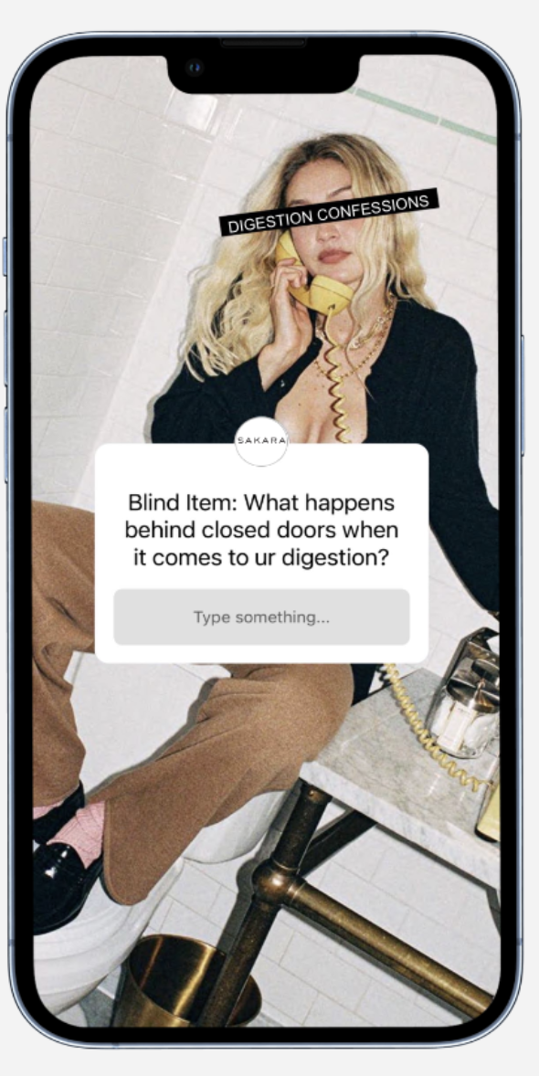 A blonde woman sitting on a toilet, talking on a yellow phone, with a white brick wall behind her. She is wearing a black jacket and brown pants. There is a phone booth on a marble table nearby. The phone booth question on the screen asks about what happens behind closed doors when it comes to digestion.