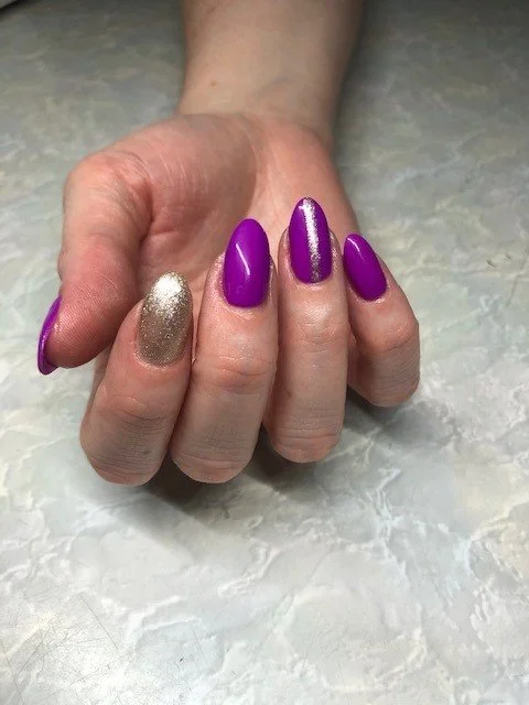 Almond nails painted purple and gold with nail art