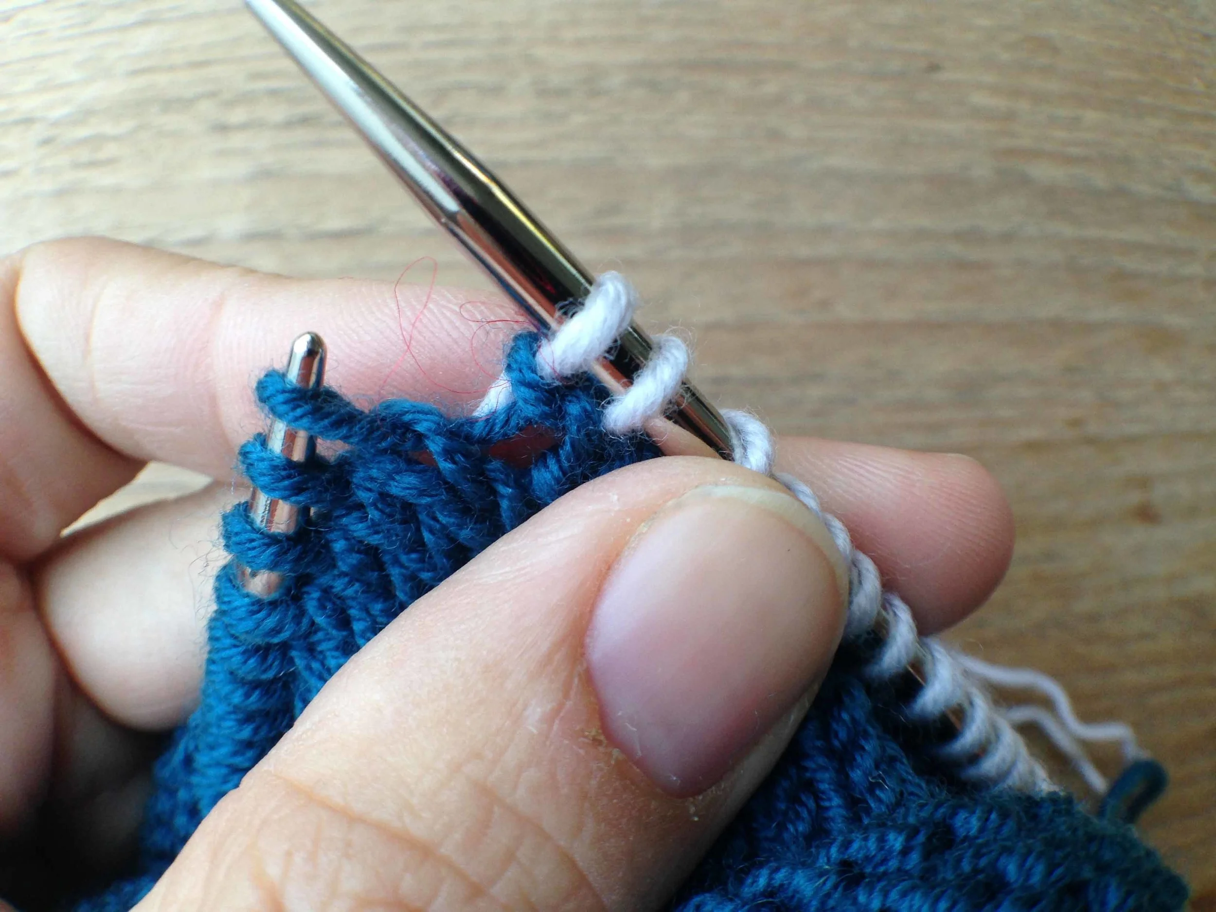 A M1 L after it has just been knit. You can tell it is a M1L rather than a M1R as the blue loop leans left on the top of the loop.