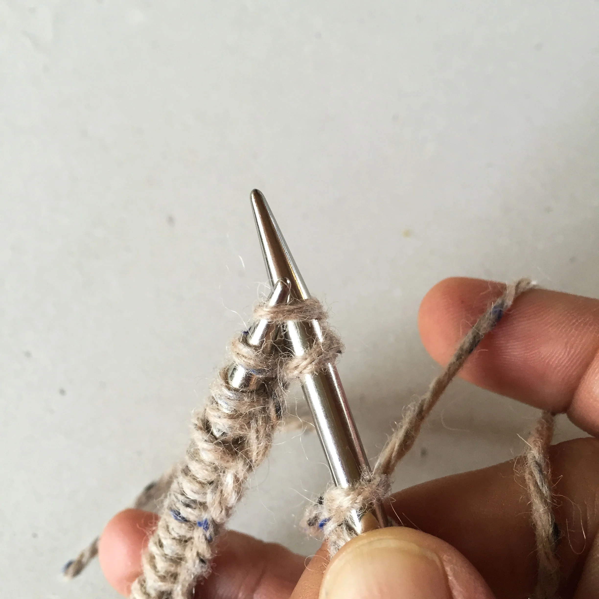 Slip the first stitch you cast on from the left needle to the right. Then knit (what was) the second stitch on the left hand needle.