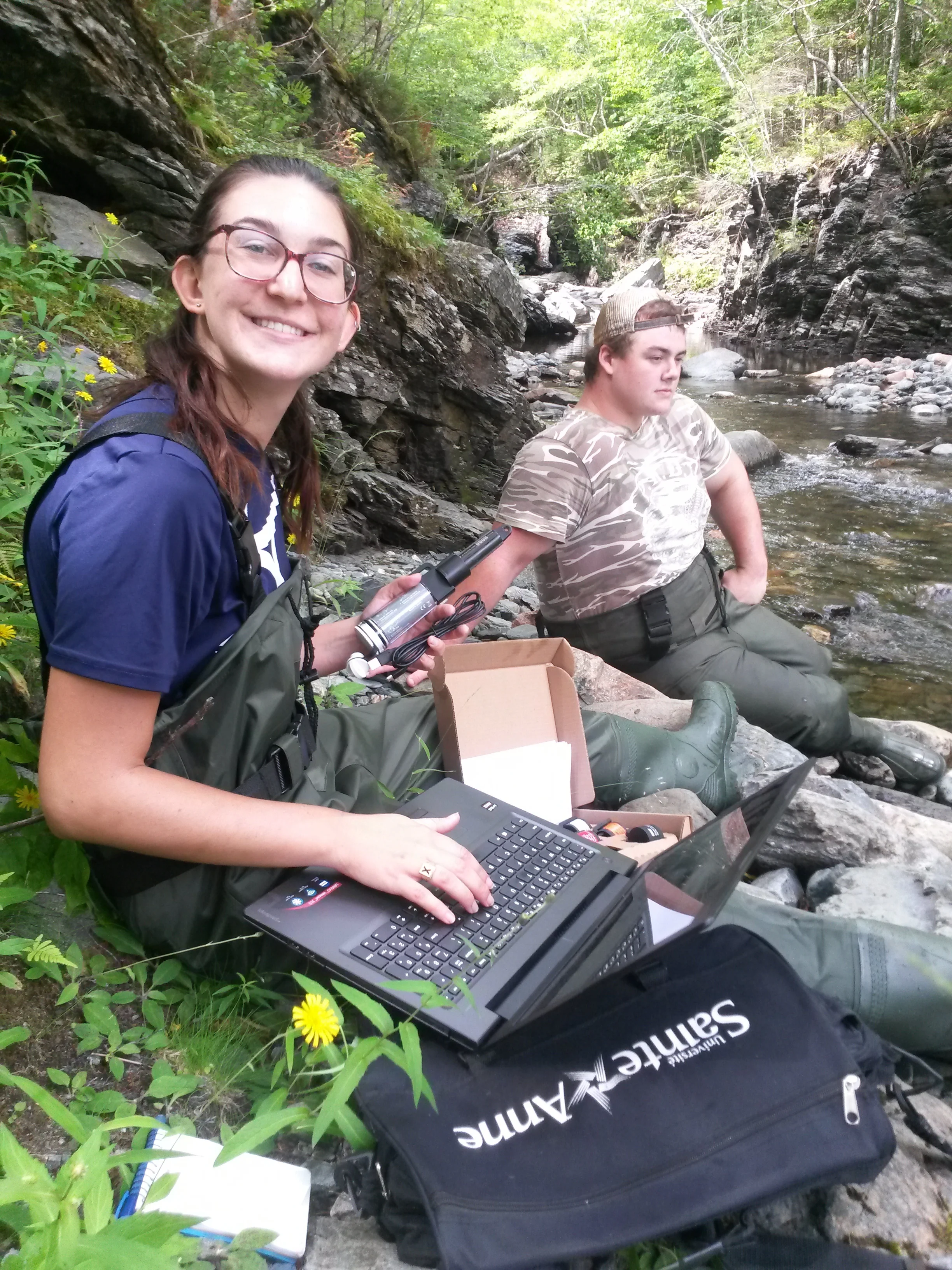 Gabrielle MacLaughlin and Jeremy Camus - summer student with the CRSA - retrieving water temperature data from one of the data loggers installed on the Cheticamp River