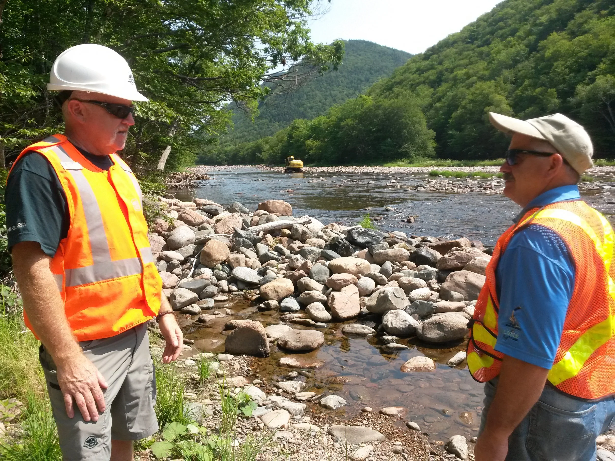 Archie Doucette (left, Parks Canada) and Charles MacInnis (project consultant in charge of restoration design and construction of instream structures) oversee work at the Faribault Brook site.