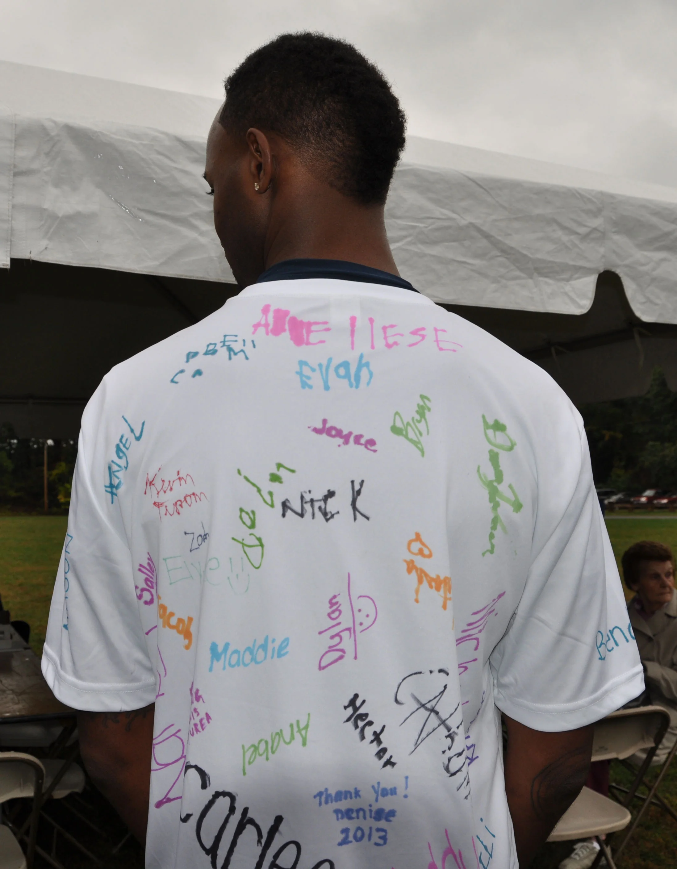 Pittman shows the back of his shirt that was signed by the patients he supports by running in the race.
