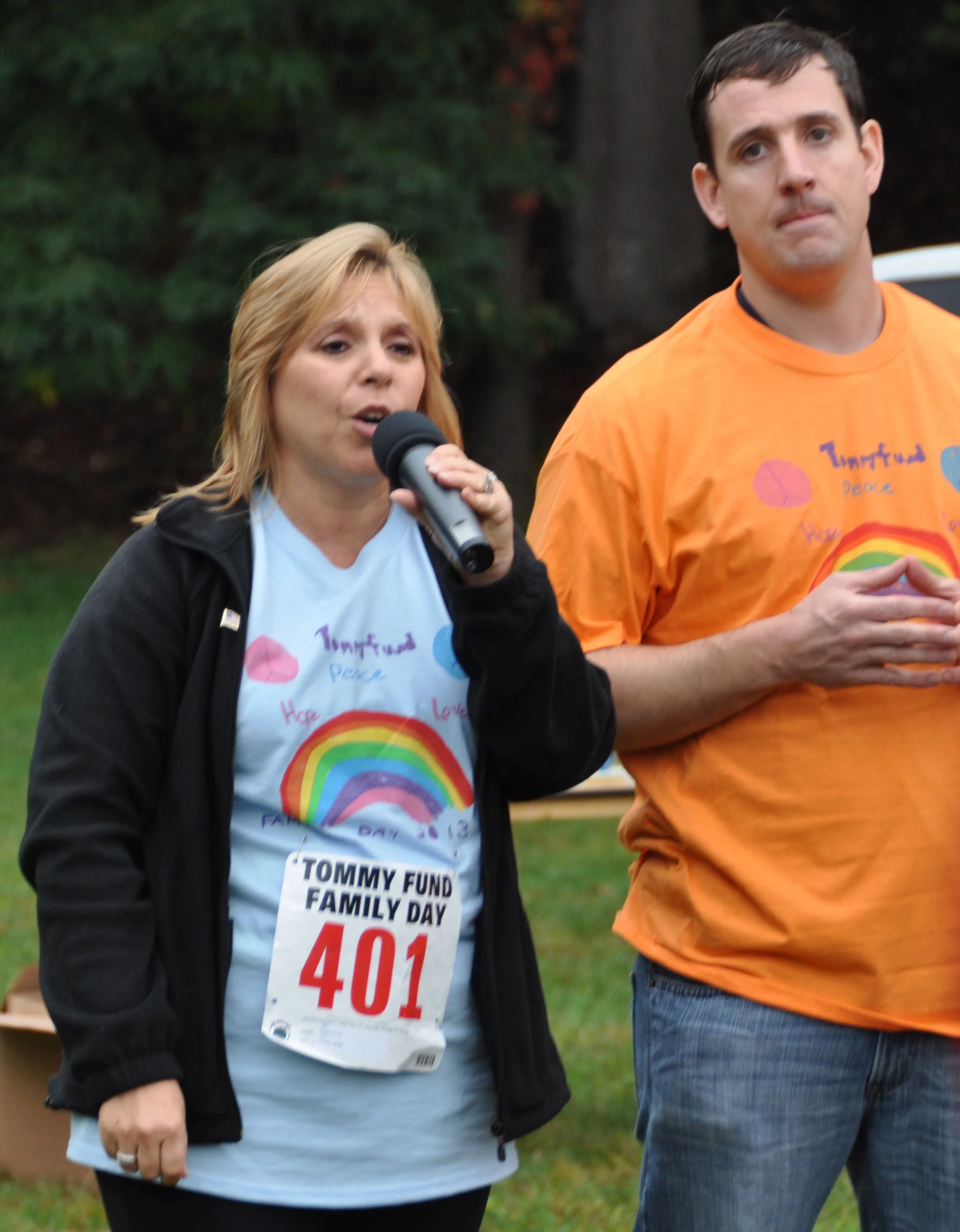 Oncology nurse Denise Carr sings the national anthem while Joe Bowman looks on.