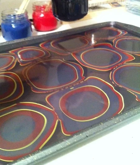 Paint floating on size, prepping for a combed pattern paper.