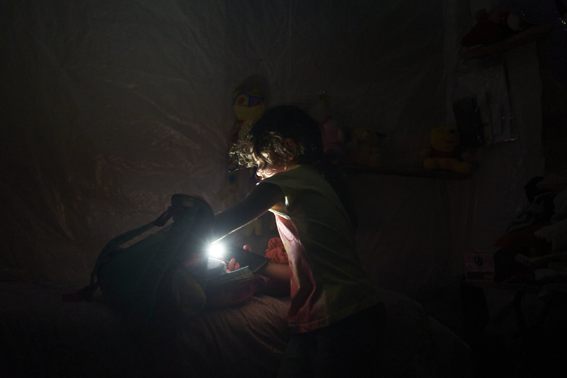 Tania’s daughter Pia prepares her school backpack on a Sunday night, with the help of her mom’s lantern, by then they didn’t have electricity in their house. April 2020
