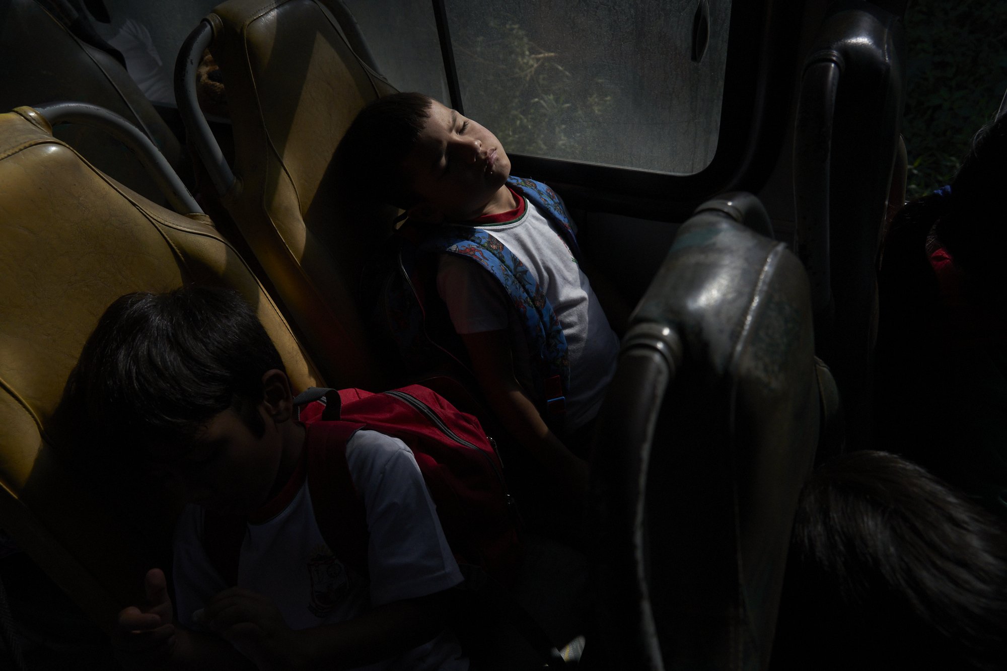 Xokleng children Xandrei Batista Braga sleeps while coming home from school, in the school bus. Jostling along a bumpy, winding road, they ride 15 miles every day school. Of the 45 students enrolled there, 35 are Indigenous. Even so, the principal