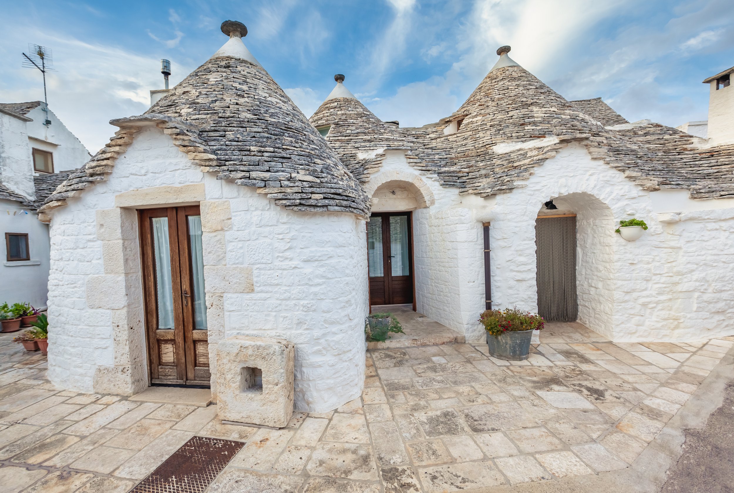 wonderful-town-alberobello-with-trulli-houses-among-green-plants-flowers-main-touristic-district-apulia-region-southern-italy-typical-buildings-built-with-dry-stone-walls-conical-roof.jpg