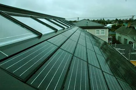 Finished roof showing the ridgeline row of solar water heating panels with the solar array below.