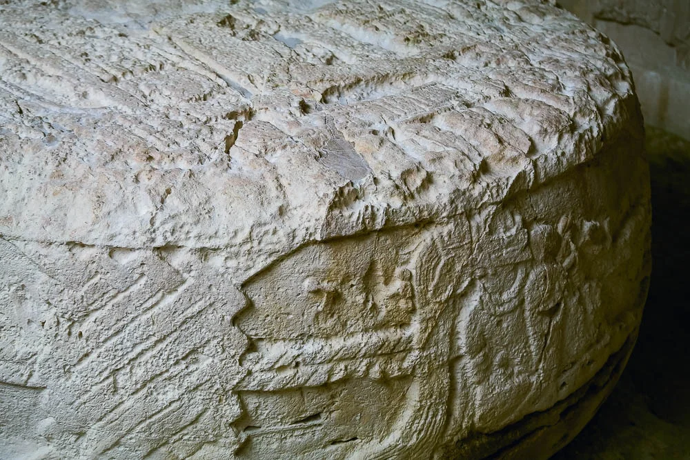 circular stone altar with intricate carvings of secenes from Maya life