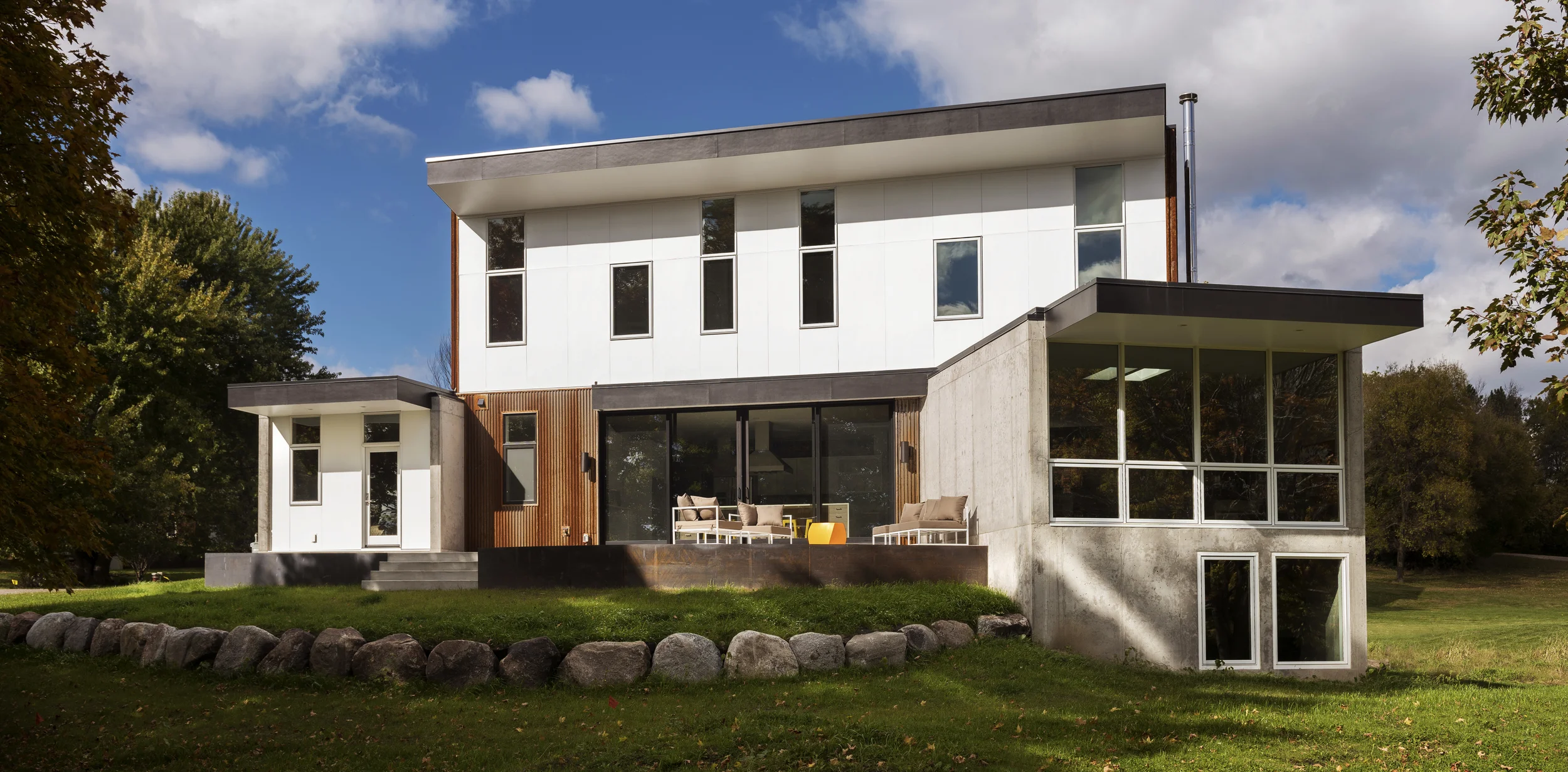 INDEPENDENCE HOUSE Located on the site of a former farmhouse, this compact modern home takes formal and material cues from the landscape and agricultural structures of the surrounding area. The massing of the home is monolithic to the north and west, protecting it from prevailing winter winds. Openings were selectively placed to allow some filtered northern light, and framed views of the wetland to the east, with the primary focus of the large window areas being toward the south. Deep overhangs prevent solar heat gain during summer months, while floor to ceiling glass allows sunlight deep into the spaces of the home during winter months. The primary shed-like forms of the building further relate to local agricultural structures in a material and textural sense. The home is constructed with thermal mass concrete walls and corrugated core-ten siding. Inside the home features materials such as hand scraped wood and stained plywood floors. All cabinetry in the kitchen and bathrooms, as well as bedroom closets were designed using IKEA products – as a means of keeping the overall cost of the project down. Location: Independence, MN Completed: June 2014 Project Team: Bob Ganser AIA, Principal-In-Charge Ben Awes AIA Christian Dean AIA Nate Dodge Michelle Ney