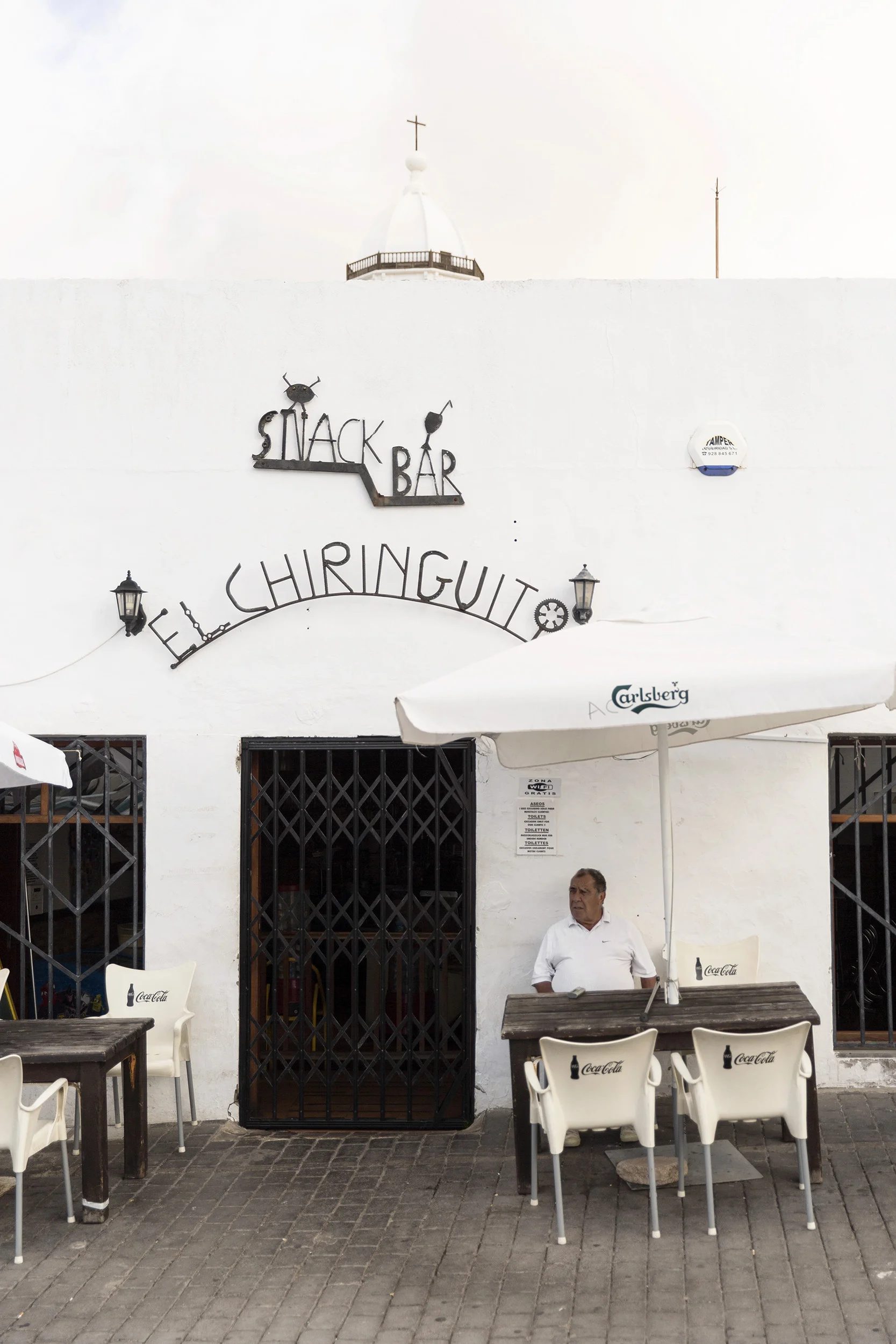 A man relaxes at a street-side cafe in the Canary Islands by Rebecca Stumpf, Denver Boulder Colorado Editorial and Commercial Photographer.