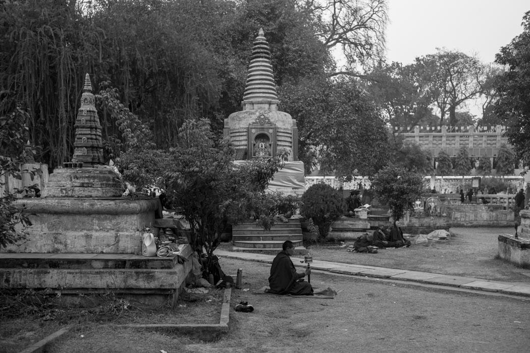 A pilgrim turning his mani wheel among the stupas on the Mahabhodi Temple grounds