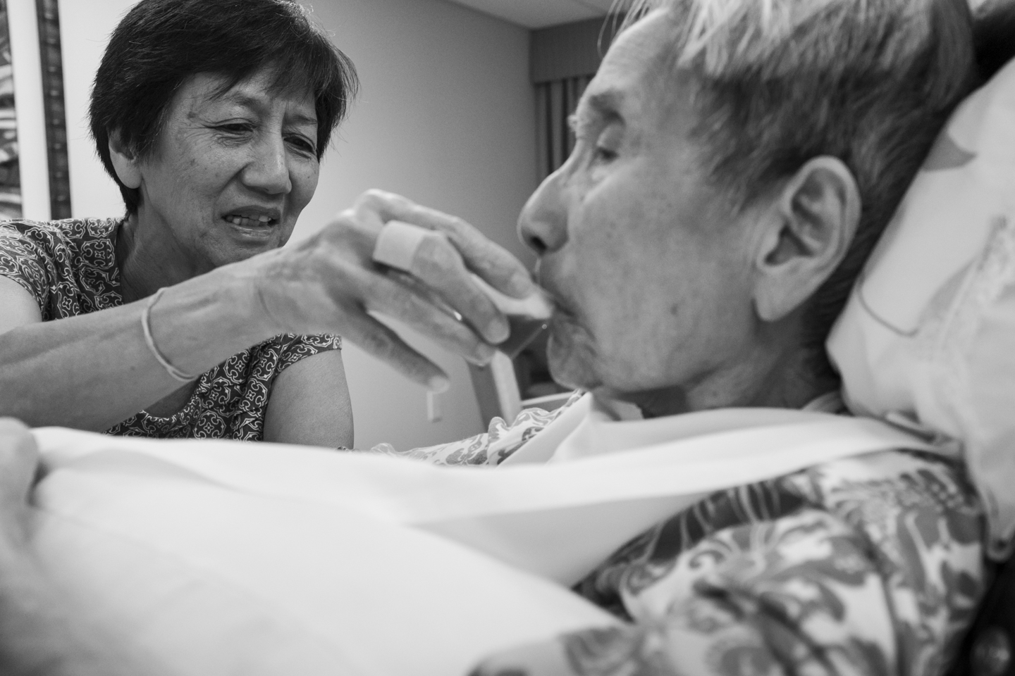 My mother, Kathy Hida, tries to feed my popo some juice to keep her hydrated. A few days before popo passed away, she stopped eating and drinking altogether. 