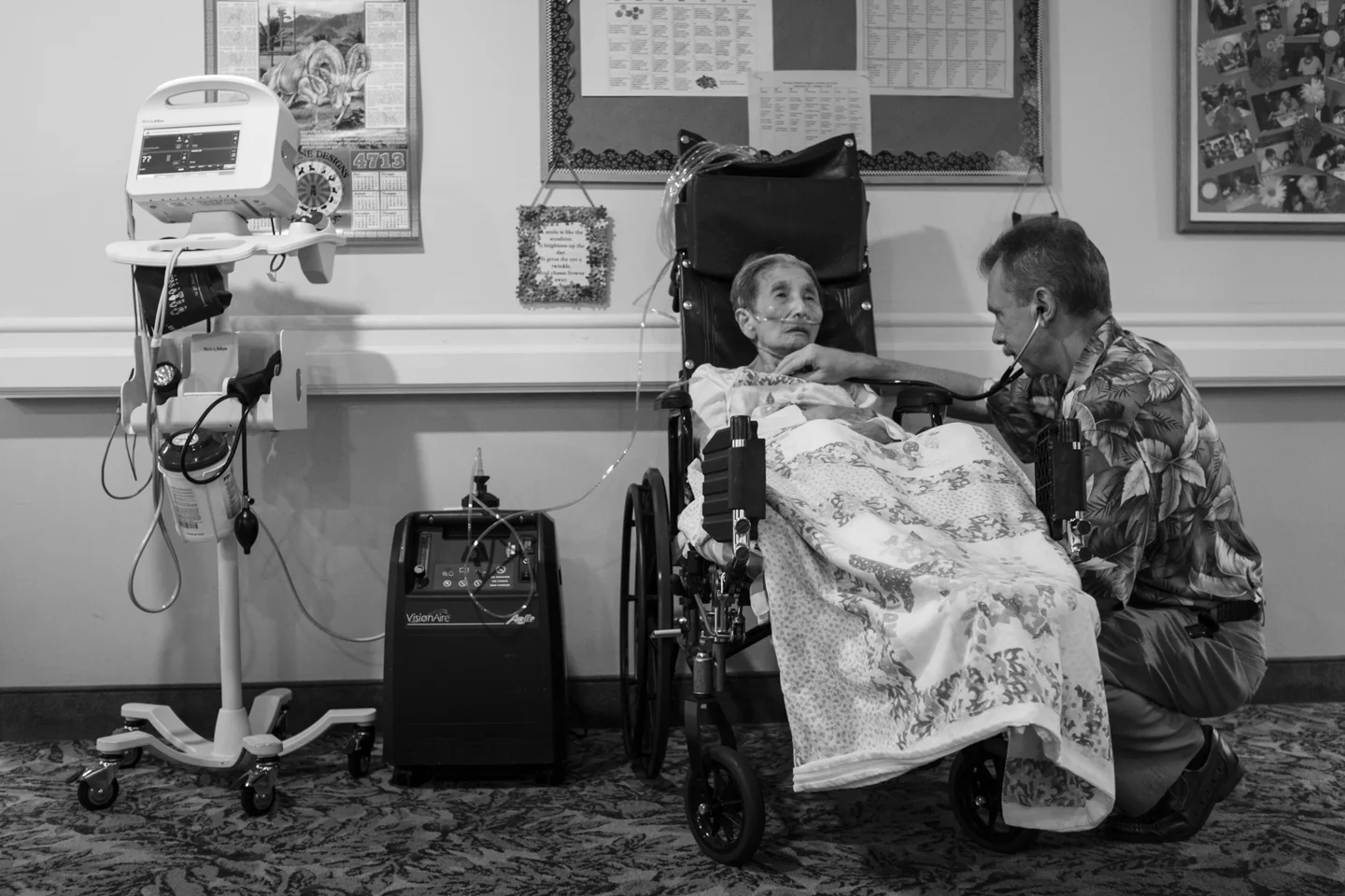 Dr. Alex listens to popo's breathing and monitors her oxygen level to make sure she's comfortable. Popo sits in a wheelchair outside of her room so the attending nurses can look after her during lunch time. 