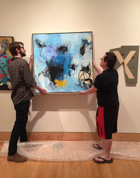 Hanging Linda's painting, "Laugh At The Night" at the 2018 Texas National Exhibition at Stephen F. Austin University. Photo courtesy of Julie Villing .