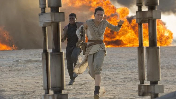 Rey (Daisy Ridley) and Finn (John Boyega) run for their lives in "Star Wars: The Force Awakens." (David James / Disney / Lucasfilm)