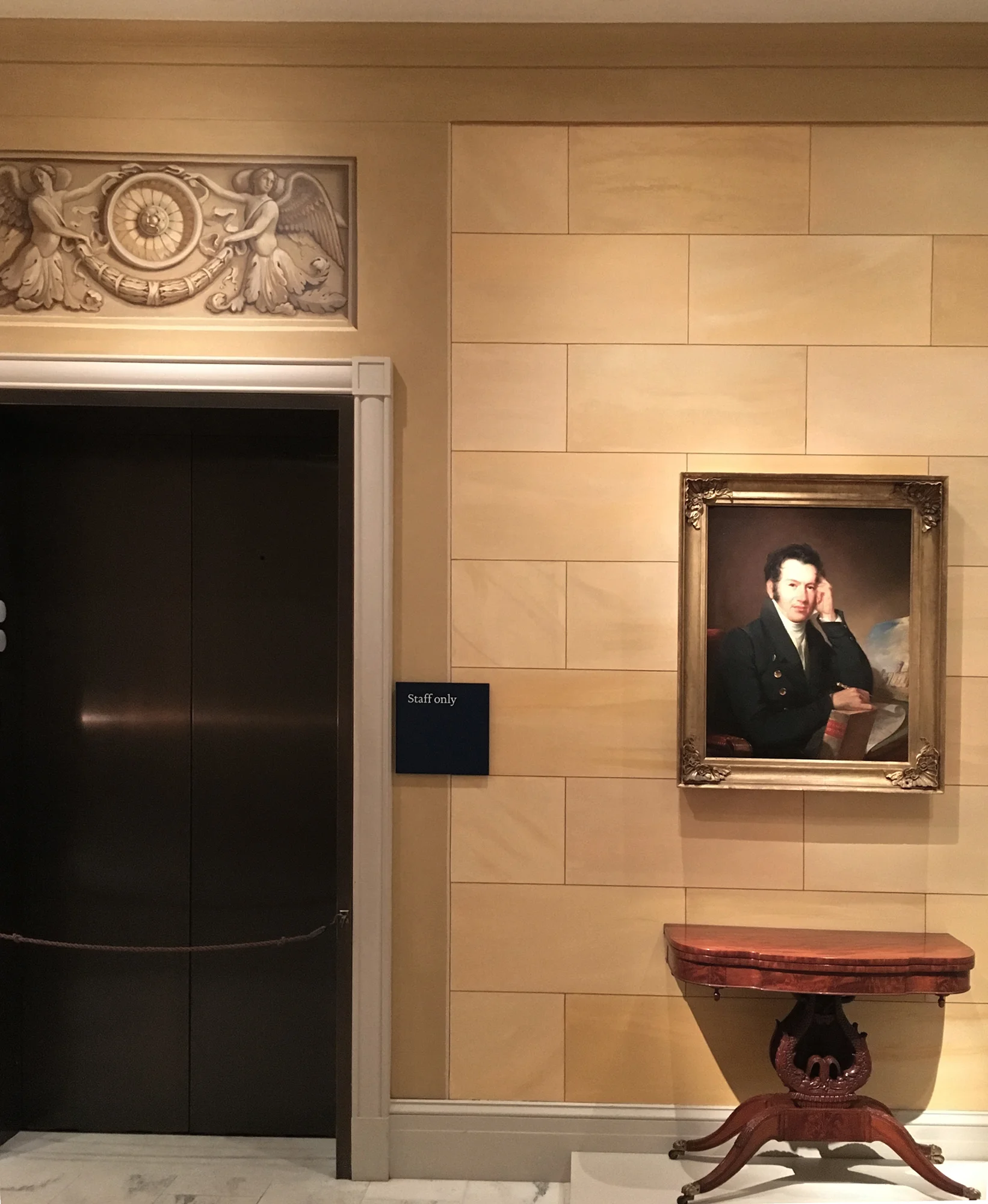 Client: Metropolitan Museum of Art, New York Langley architectural trompe l'oeil : doorway surrounds and surface decoration of one of the new Greek Revival classical galleries in the American Wing, The walls have been painted a warm ochre shade to resemble limestone ashlar (large square stones) with a grisaille painted frieze of classical winged genii and acanthus volutes.
