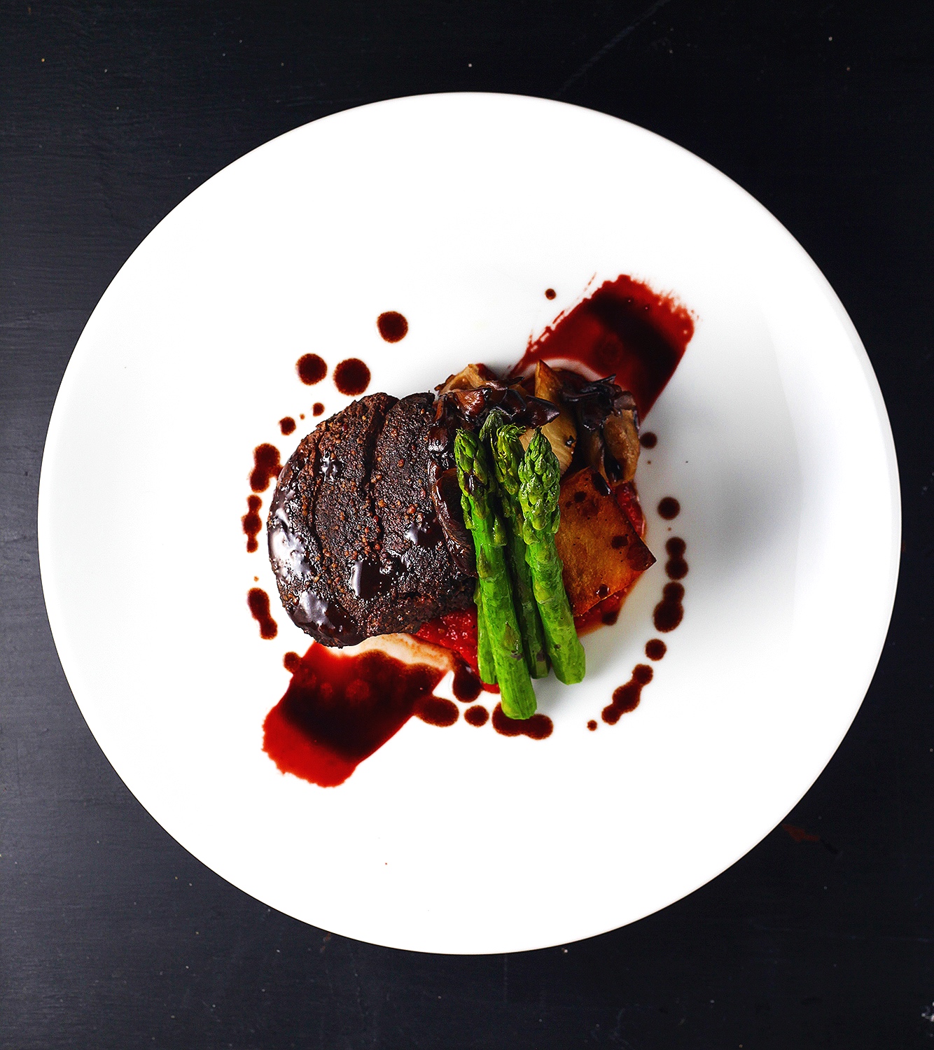 Beef tenderloin over polenta with red wine reduction and topped with asparagus
