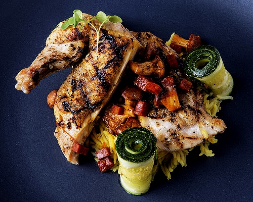 Quartered roasted chicken with rice, zucchini and chanterelle