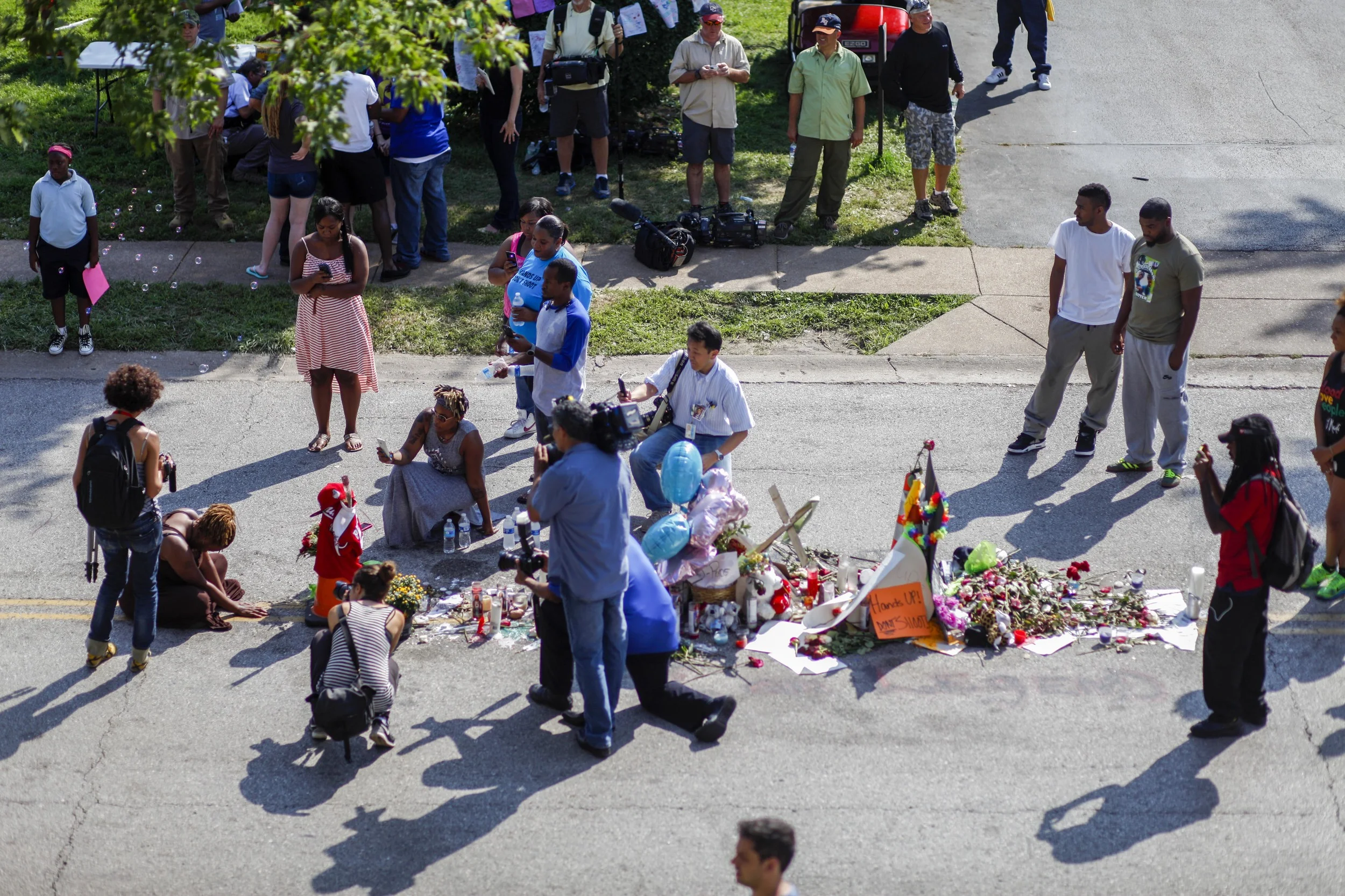 A woman, left, sings at a memorial where Michael Brown was shot on August 9, 2014 on Canfield Drive. Photographed August 20, 2014 in Ferguson, MO.