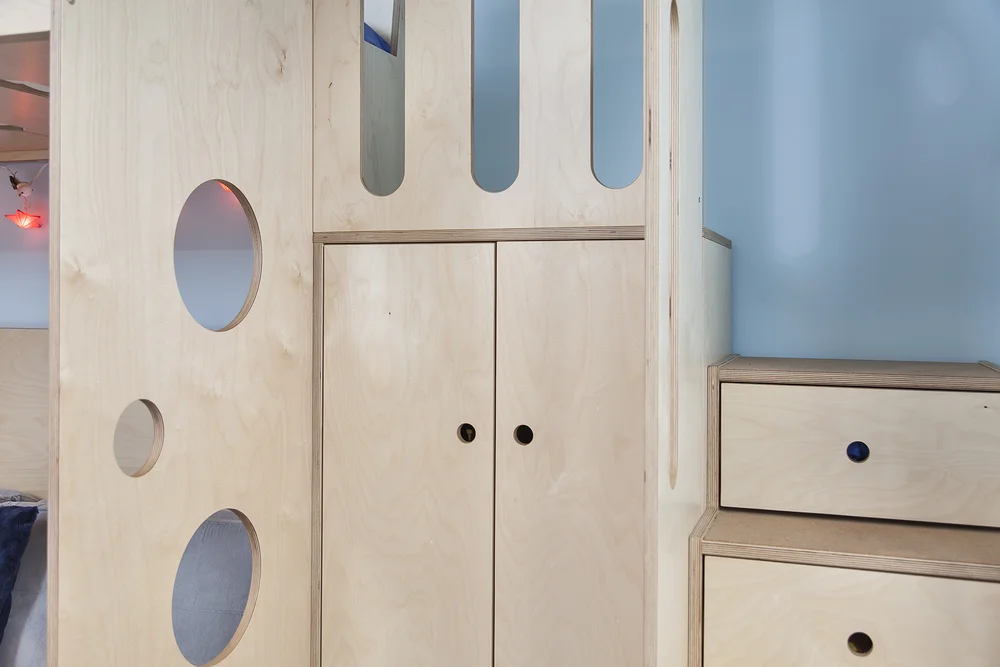 Light wooden furniture with playful circular cutouts, including a tall wardrobe and a drawer unit.