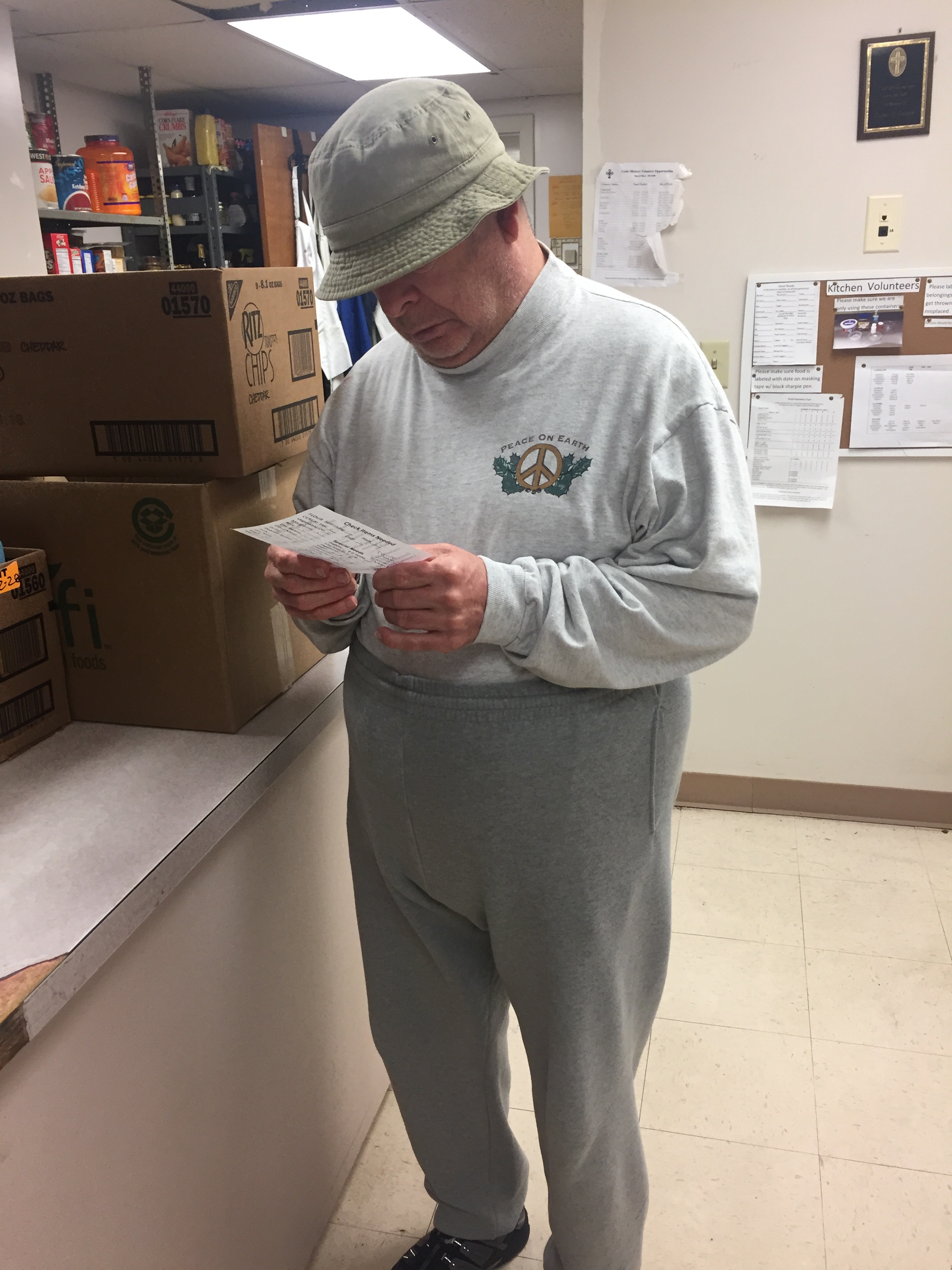 Volunteer Tim O'Connor looks over a list of foods requested by a client at the Downtown Crisis Ministry. Tim enjoys packing food boxes and bags for the clients, because he was one himself several years ago.