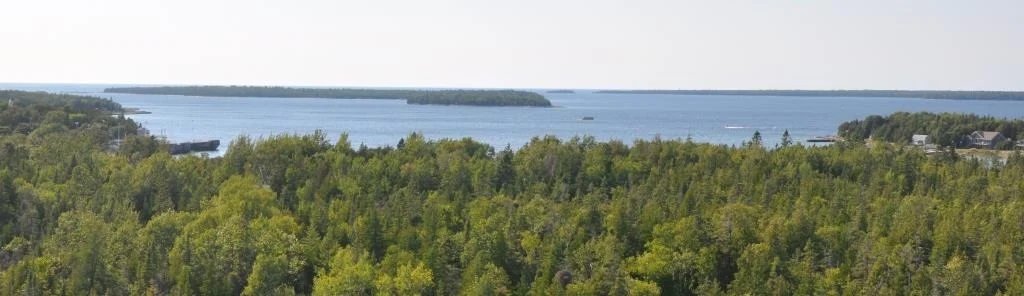 A view over Fathom Five park, with the harbour of Tobermory to the left, the open water of Lake Huron beyond and Georgian Bay to the right. The wreck of the Alice G lies in the centre foreground.