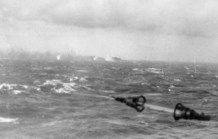 The last known photograph of Bismarck, shells falling around her and trailing smoke, taken from the railing of a British ship on 27 May 1941 (Lt J.H. Smith, RN, IWM A 4386).