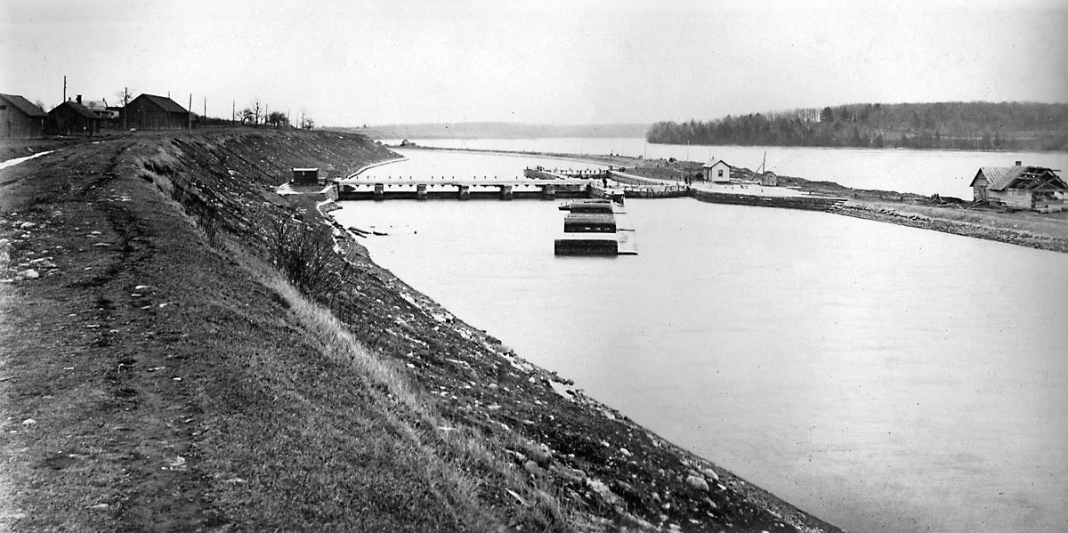 A photograph of Lock 21 looking east, thought to have been taken about 1904. The buildings to the left are on the site of the present information pavilion, with the water level today being about a metre higher than the top of the embankment. Our dive in the video took us down the slope to the railing at the top of the weir, then over the railing to the bottom of the canal, through the sluice gates (underwater in this photo) and out the other side (photographer unknown).