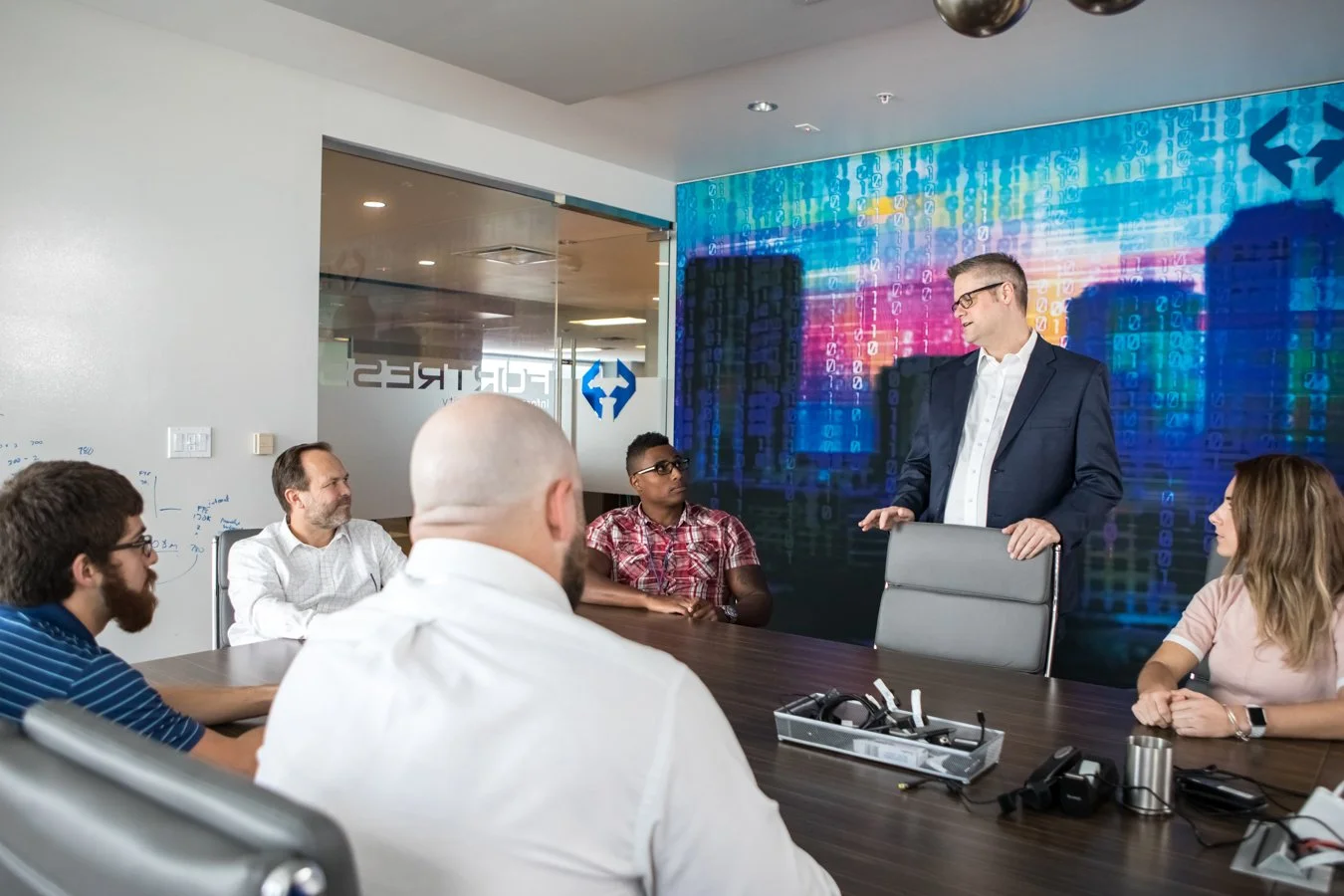 Business team participating in a meeting in a conference room with a digital futuristic cityscape and code background on the wall.