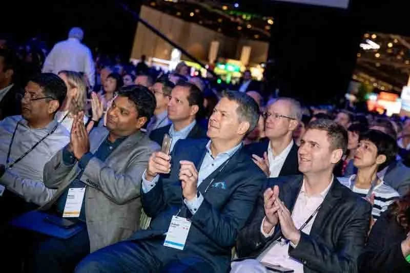 Audience of diverse professionals sitting and clapping at a conference or event.