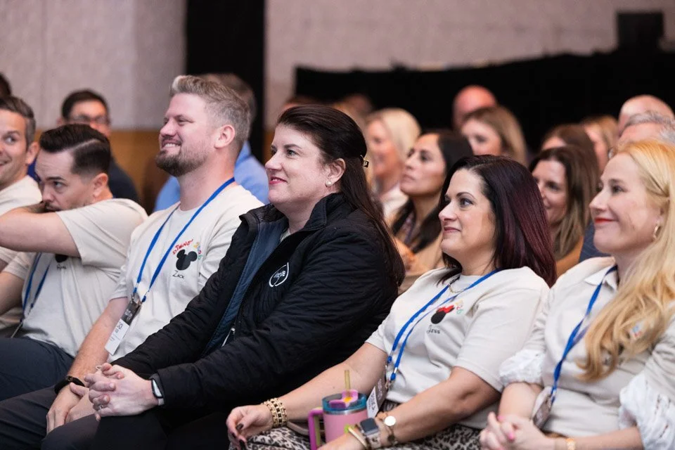 People seated and listening attentively at an indoor event or conference.