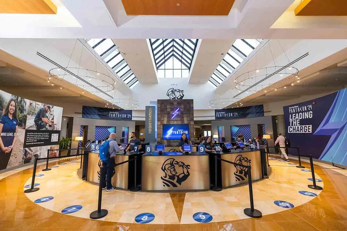 Registration area at a conference or event with multiple check-in counters, digital screens, and attendees, featuring branding for PantherCon 2024.