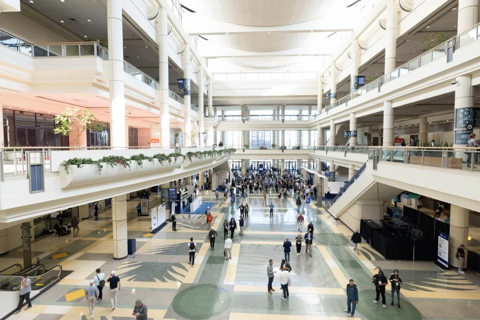 Inside a large, multi-story airport terminal with people walking and gathering.