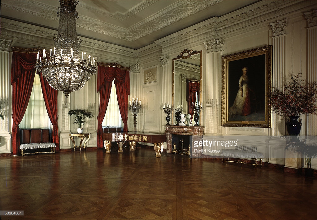 This photo shows the East Room as it appeared under President and Mrs. Franklin Roosevelt, ca. 1938, with the new, and, on the whole, less delicately treated, Steinway art case grand. According to a 1937 special in The New York Times , the earlier gold drapery was chosen by Mrs. Theodore Roosevelt and was a deviation from the original 1902 design, with which, according to the article, the red damask pictured here was 'in harmony'. This has not been verified. It is useful to note, however, that while the red does not necessarily offend, the square shape, plain mahogany veneer, and large, detached eagle legs of the 1938 piano are made rather clumsy by the comparative grace and splendor of the room. (Photo by Dmitri Kessel, contrib., The LIFE Image Collection, Getty Images.)