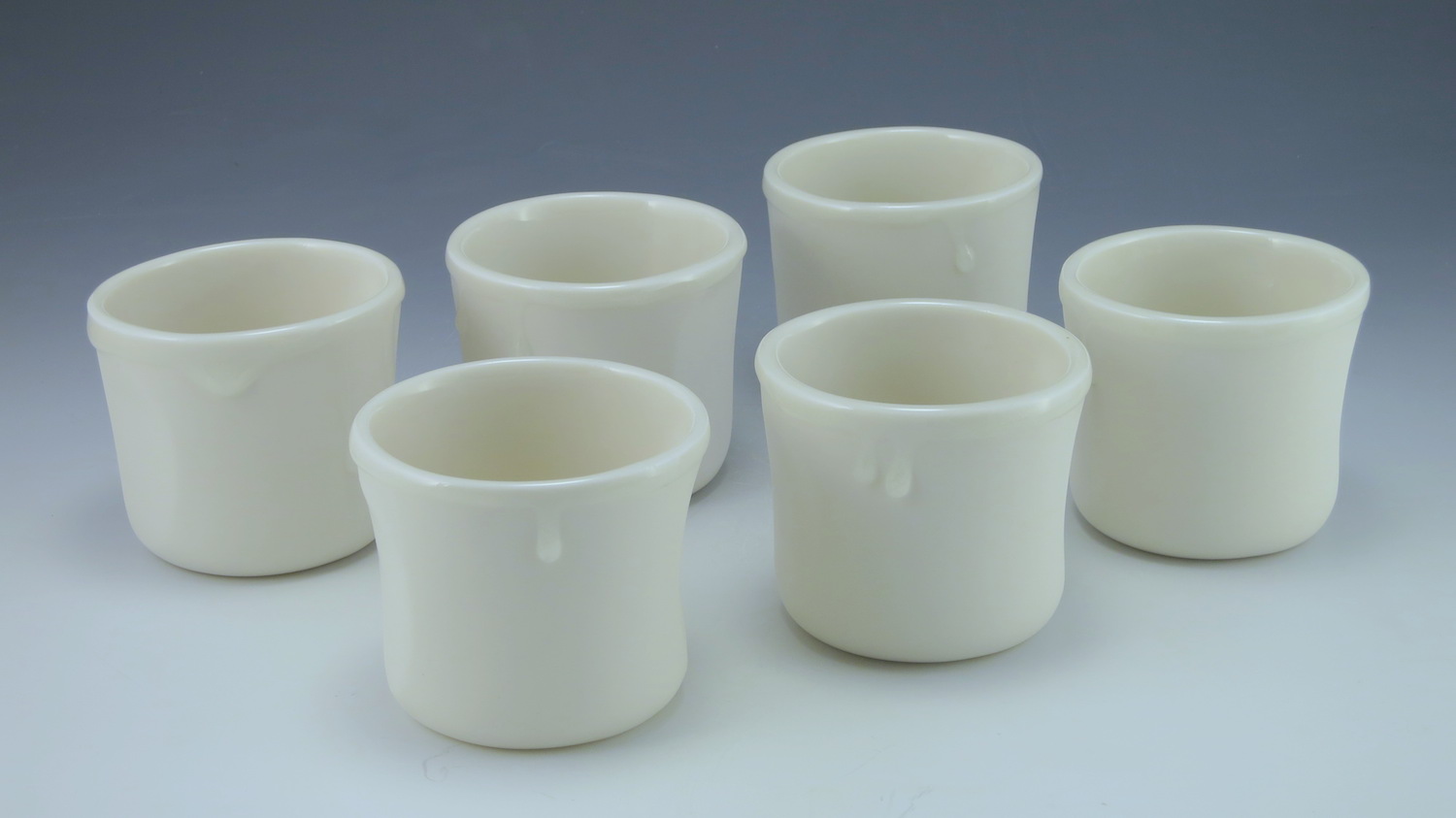 WHITE WHISKY A pure white 5oz cup, with a clear juicy glaze that slops over the rim and runs in heavy drips down the side. Thumb and forefinger cut outs help the cup nestle in your hand, as does the little tuck on the underside of the cup. Made from my purest porcelain slip, these cups are sanded at every stage and their smooth, silky surface caresses your fingers, while the glaze drips give them something to play with. Made with late night whiskey sessions in mind.