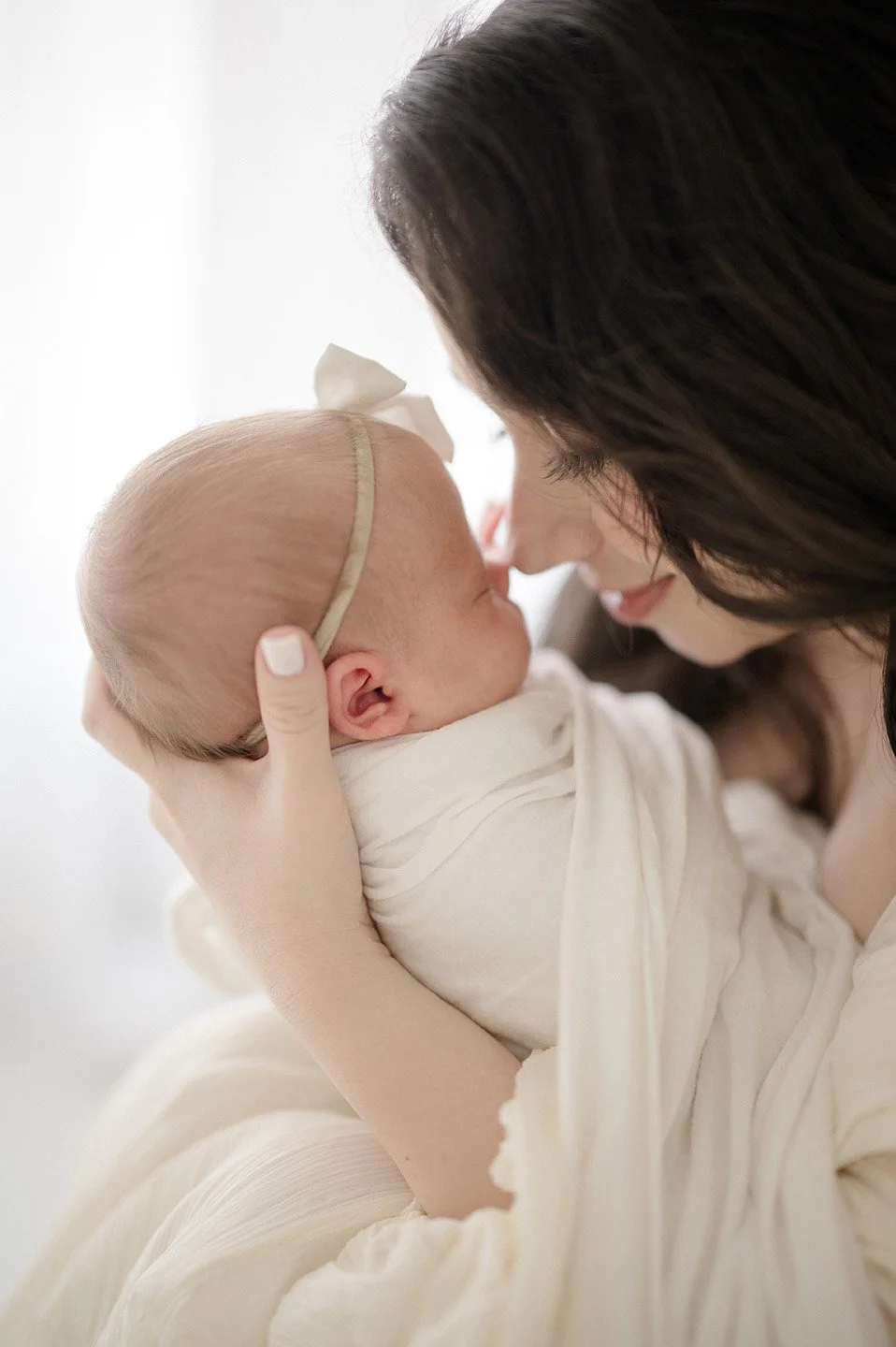 Close-up of a woman holding and cuddling a newborn baby girl.