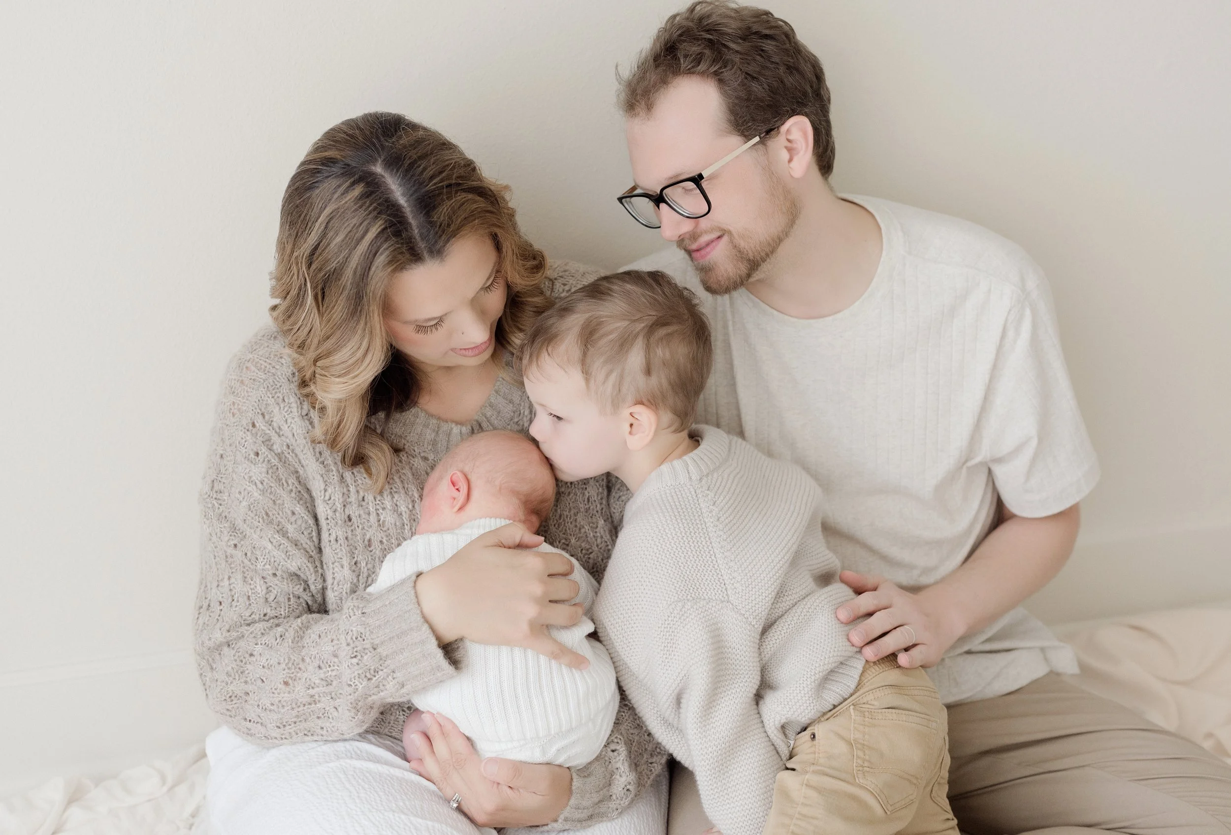 Family of five, including four children, gathered closely and sharing a tender moment, with the mother holding a newborn and the others leaning in affectionately. Baton Rouge Maternity Newborn and Family Photographer 