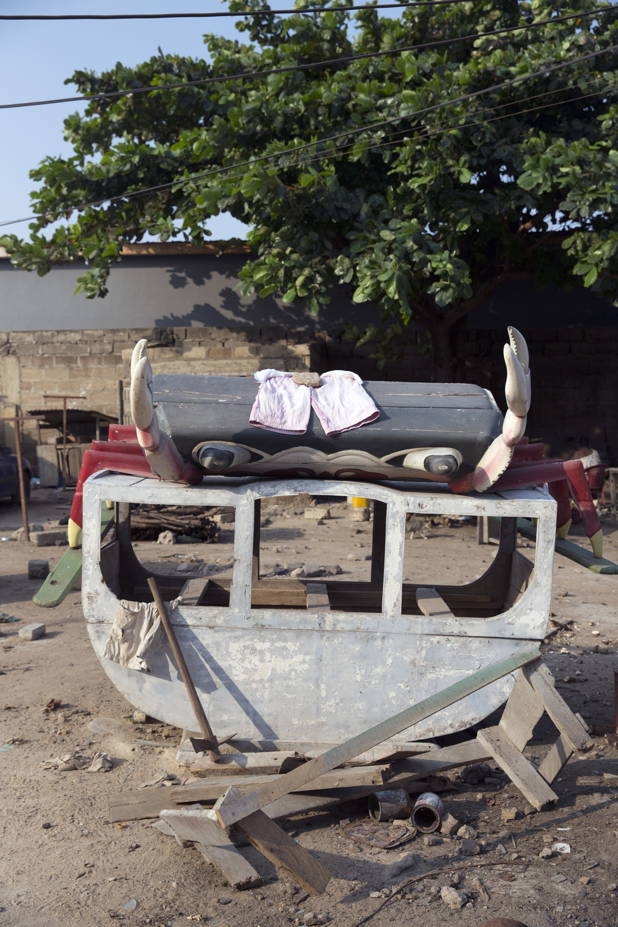 A pair of shorts dry atop a crab (coffin?), which is then attached to a boat (other coffin?). 