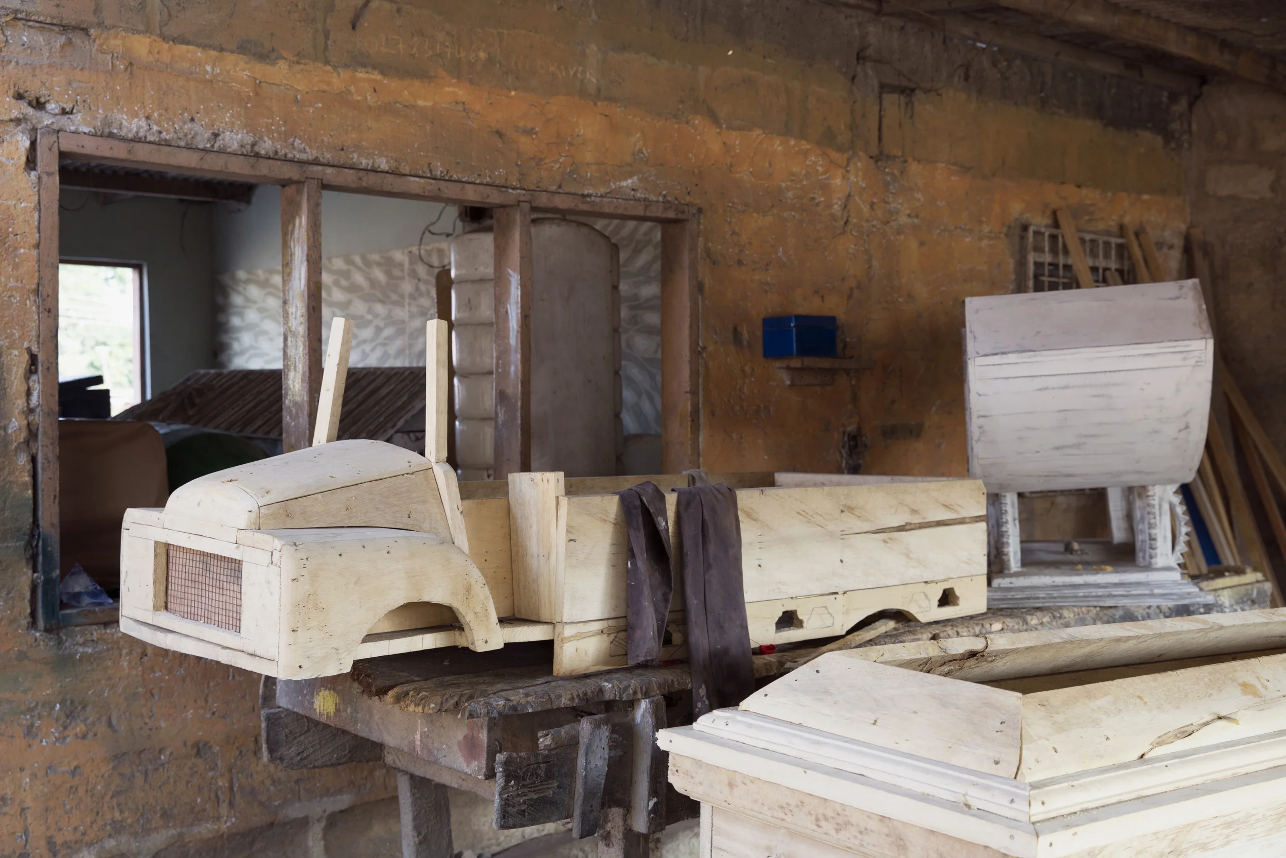 An unfinished truck coffin sits next to a cradle (???) coffin.