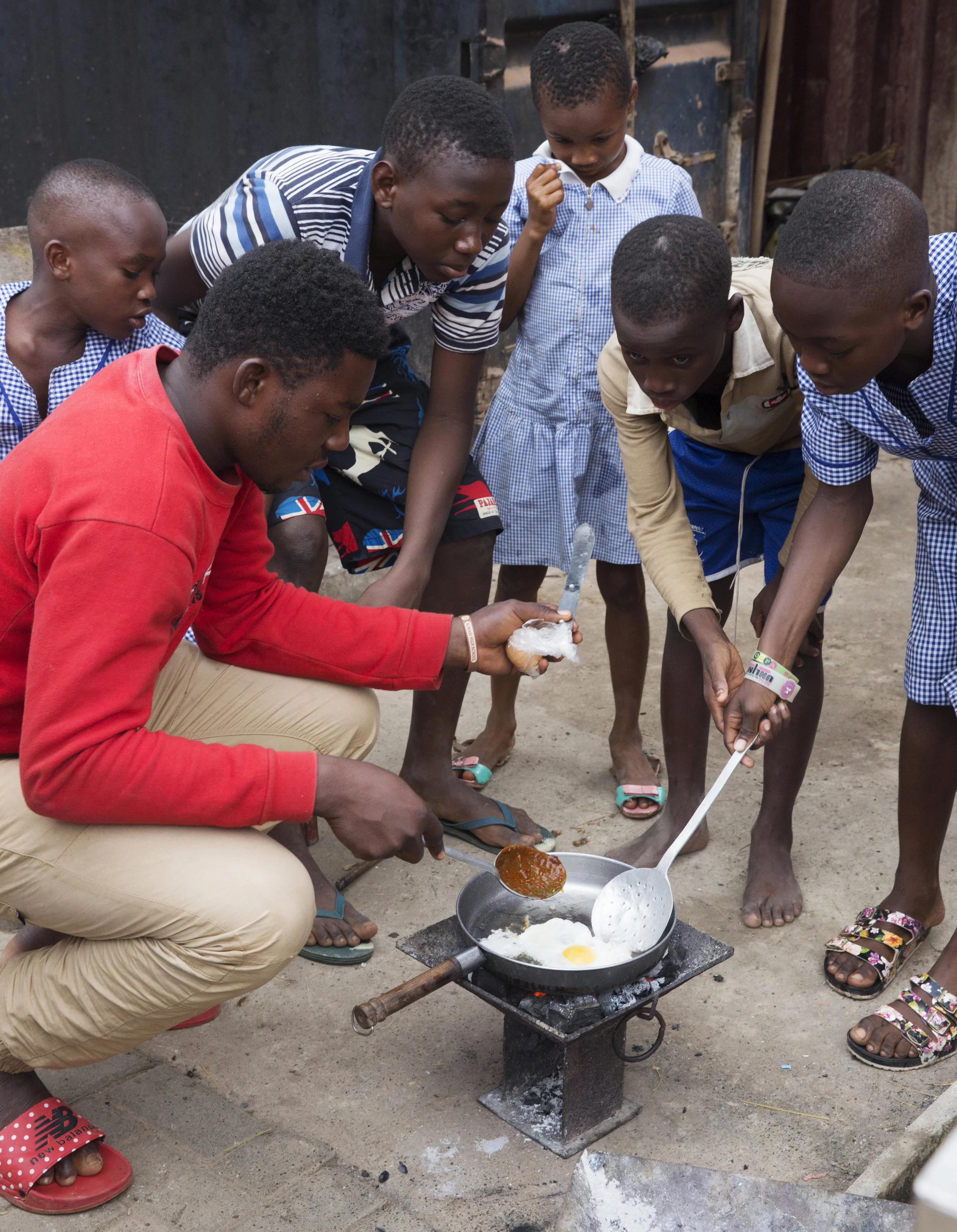 Sir Dennis helps the kids to fry the eggs that they will later chop up and add to their spaghetti.