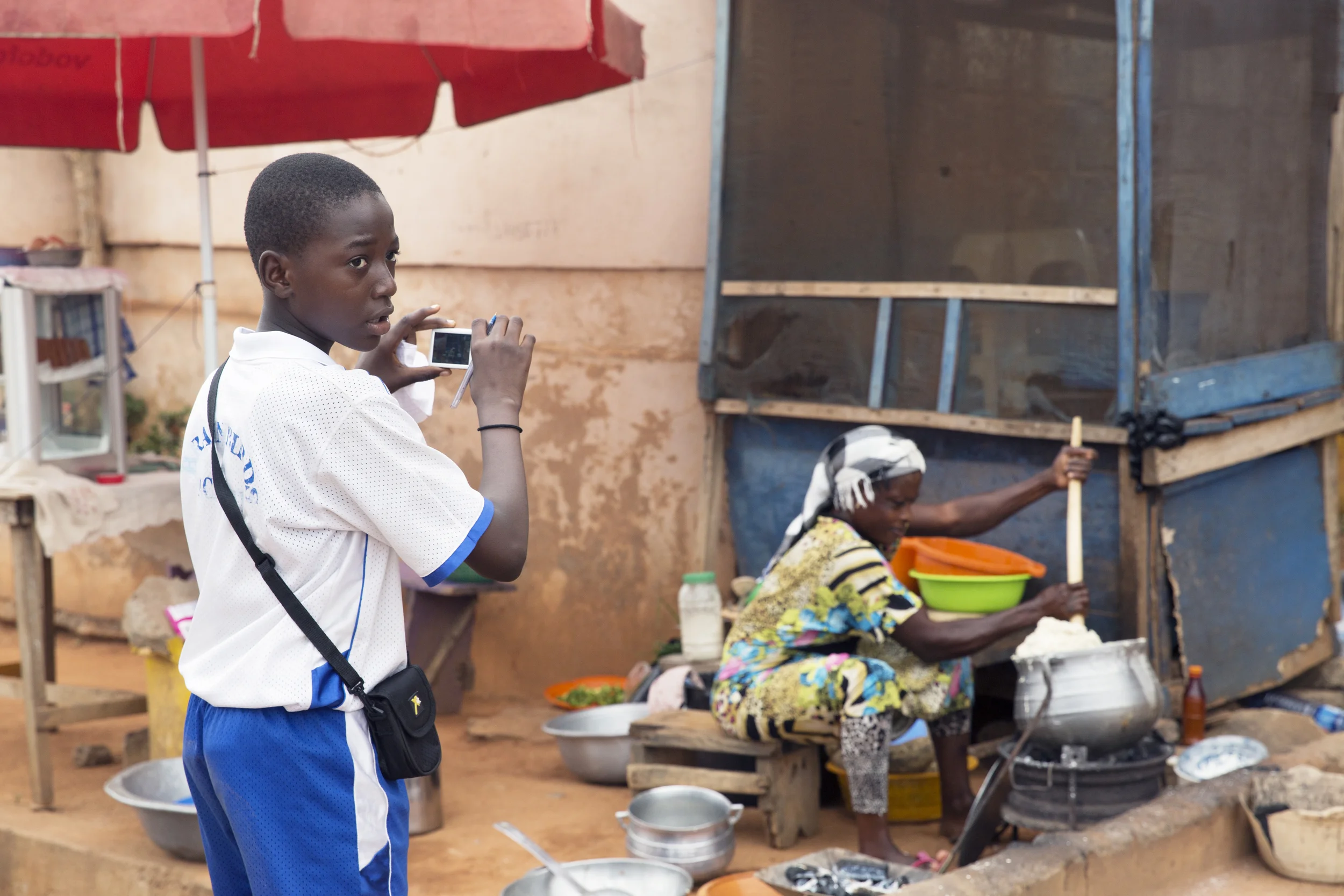 Hakeem photographs a woman making banku across from the school. 