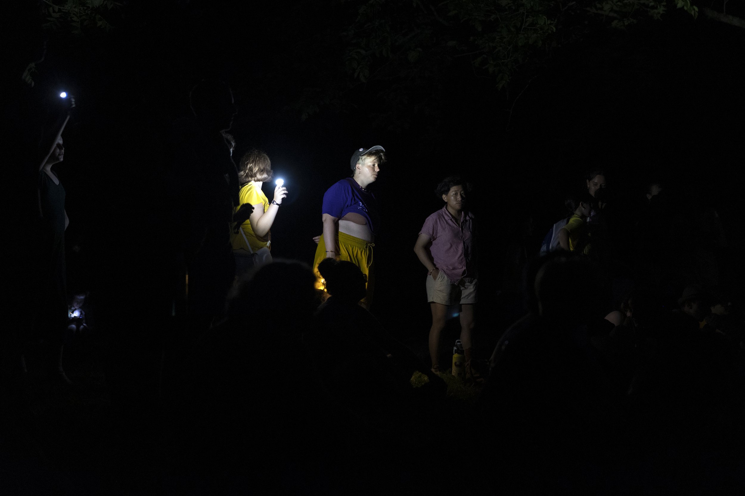  Counselor Indigo Johnson (center) is illuminated by campers waving their flashlights at closing circle. 