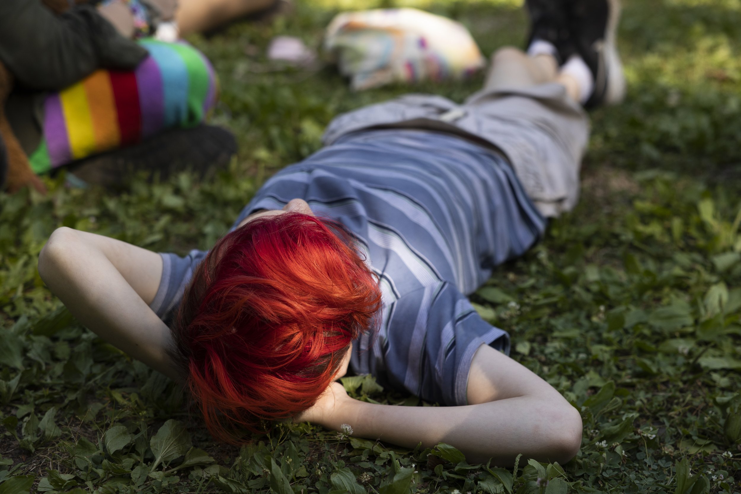  Vallon (they/them) lays in the grass during the camp talent show. 