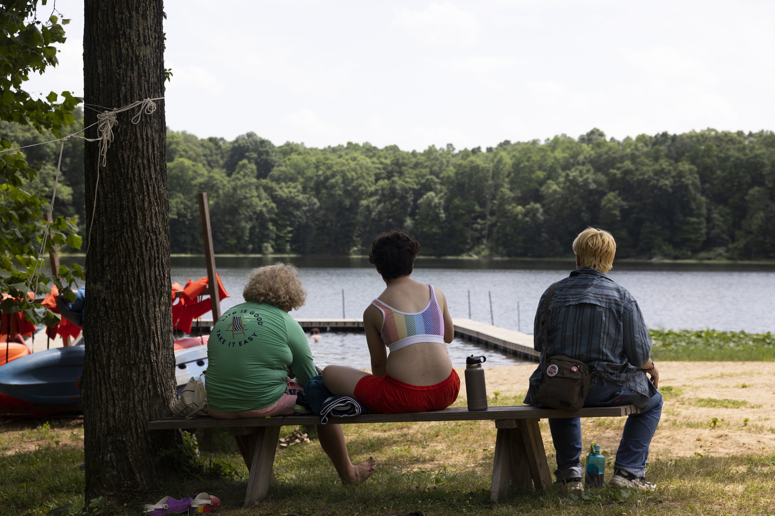  Campers (from left) Oliver (he/him), Avram (he/him) and Fern (he/him) sit beside the lake. 